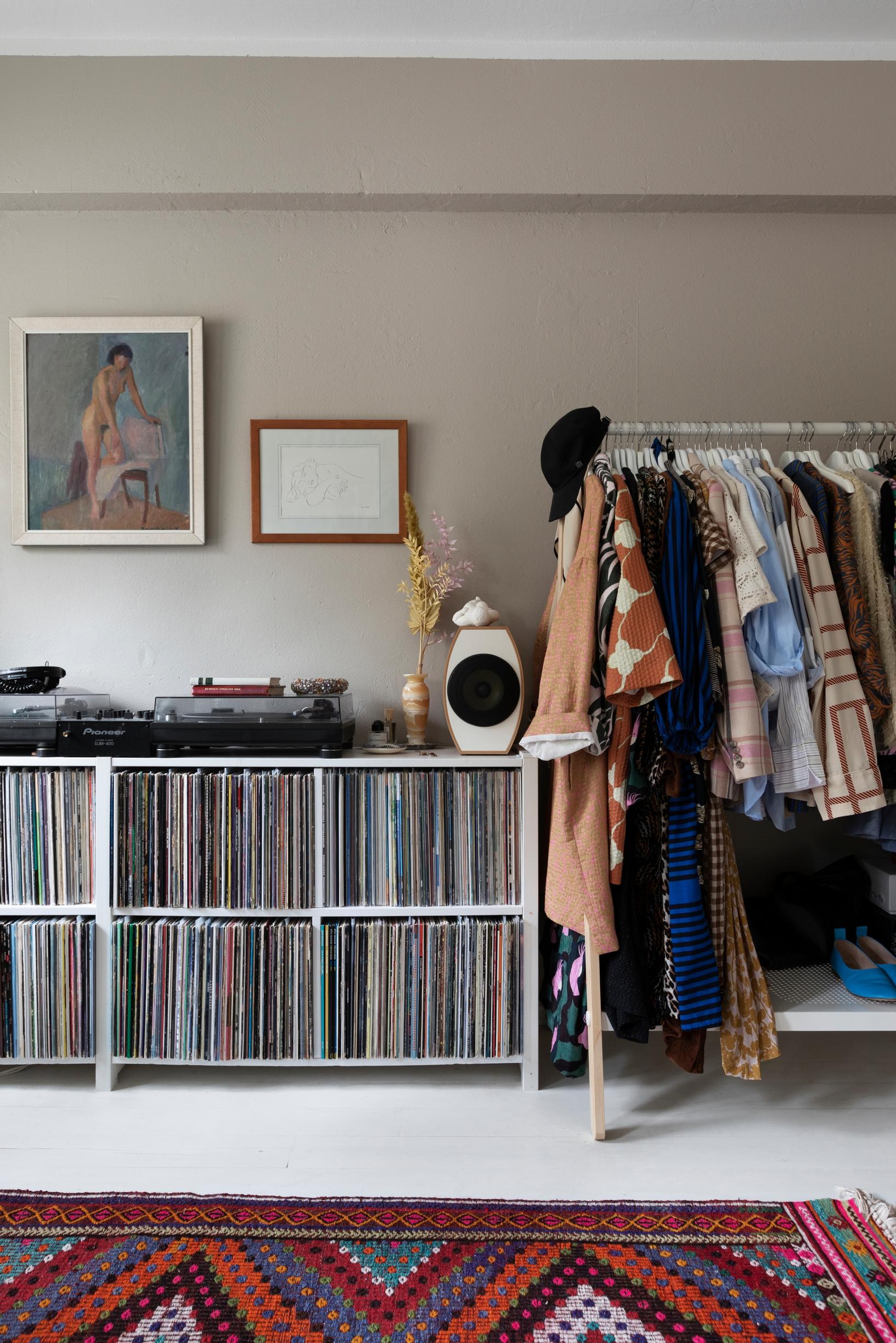A shelf with a vinyl collection and favorite clothes on a rack