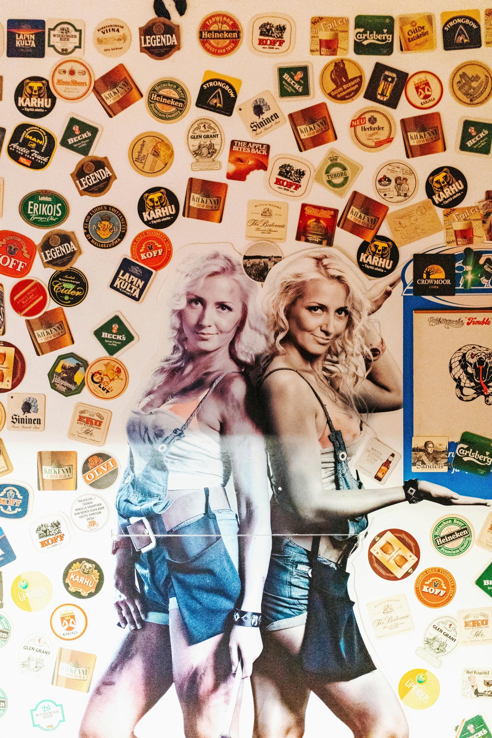 the wall is decorated with coasters and a decal of two waitresses