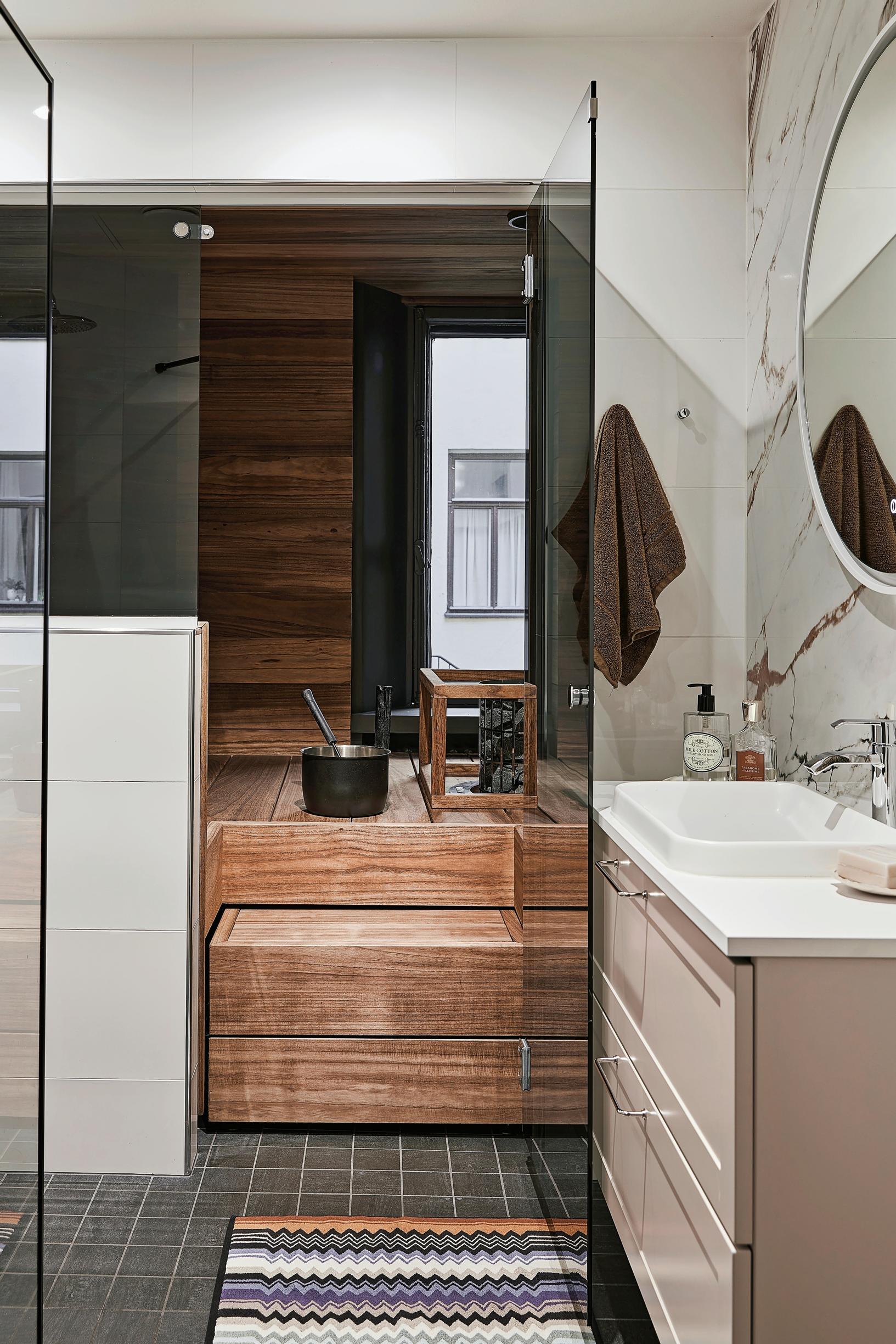 A modern sauna and bathroom with a marble-patterned tiled wall