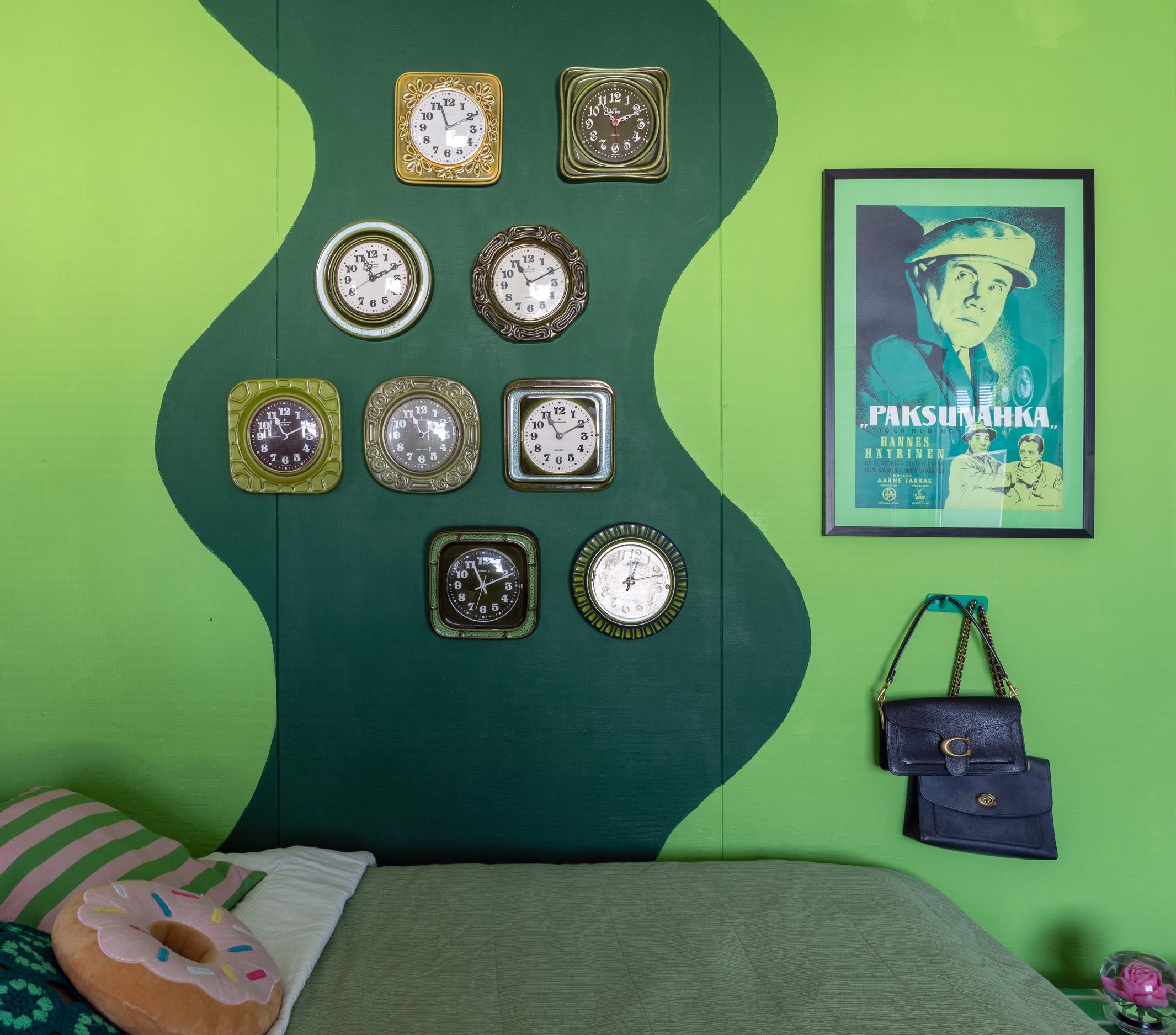 Clocks on a green wall.