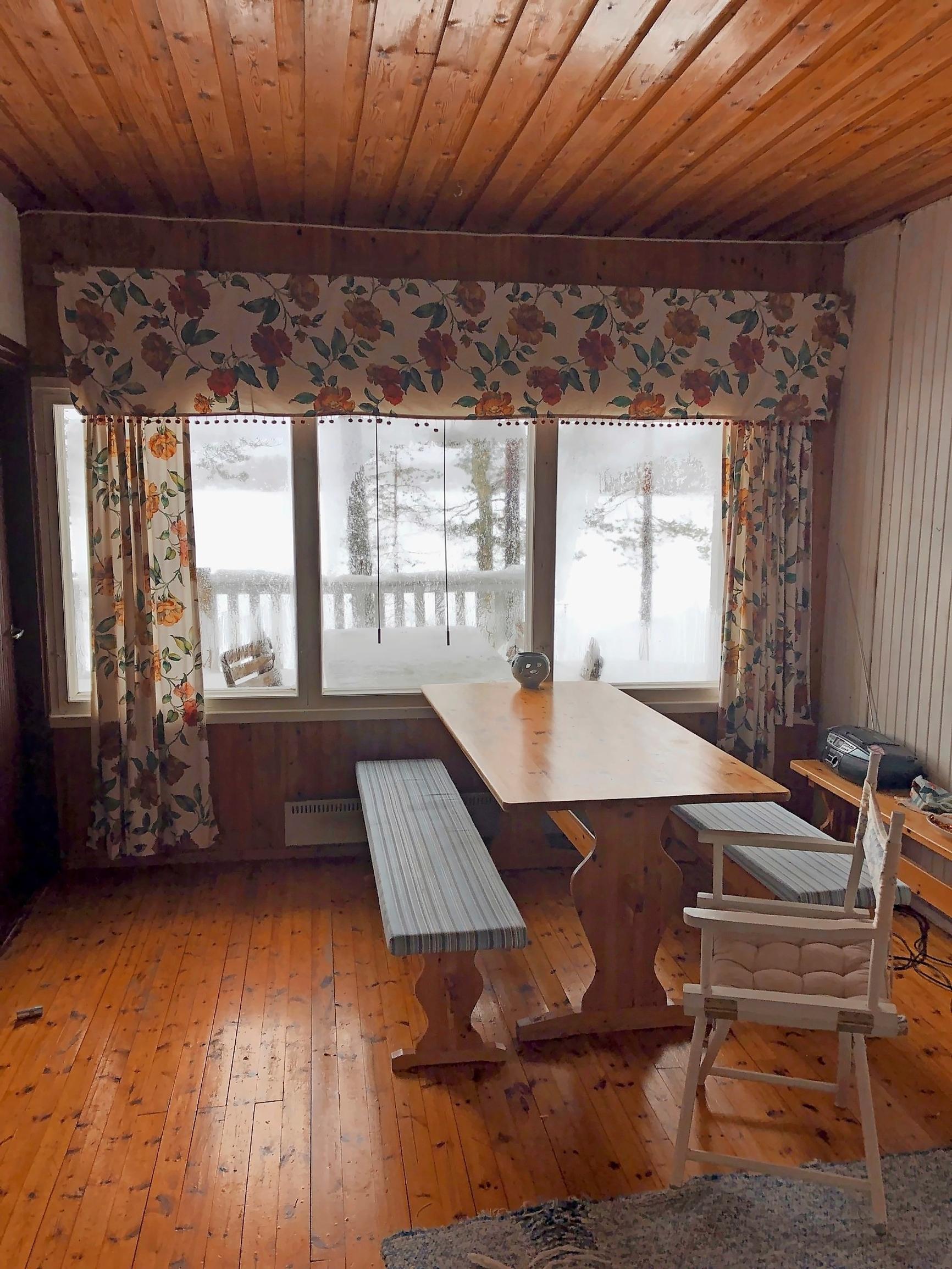 An old farmhouse table, floral curtains, and a view of the lake