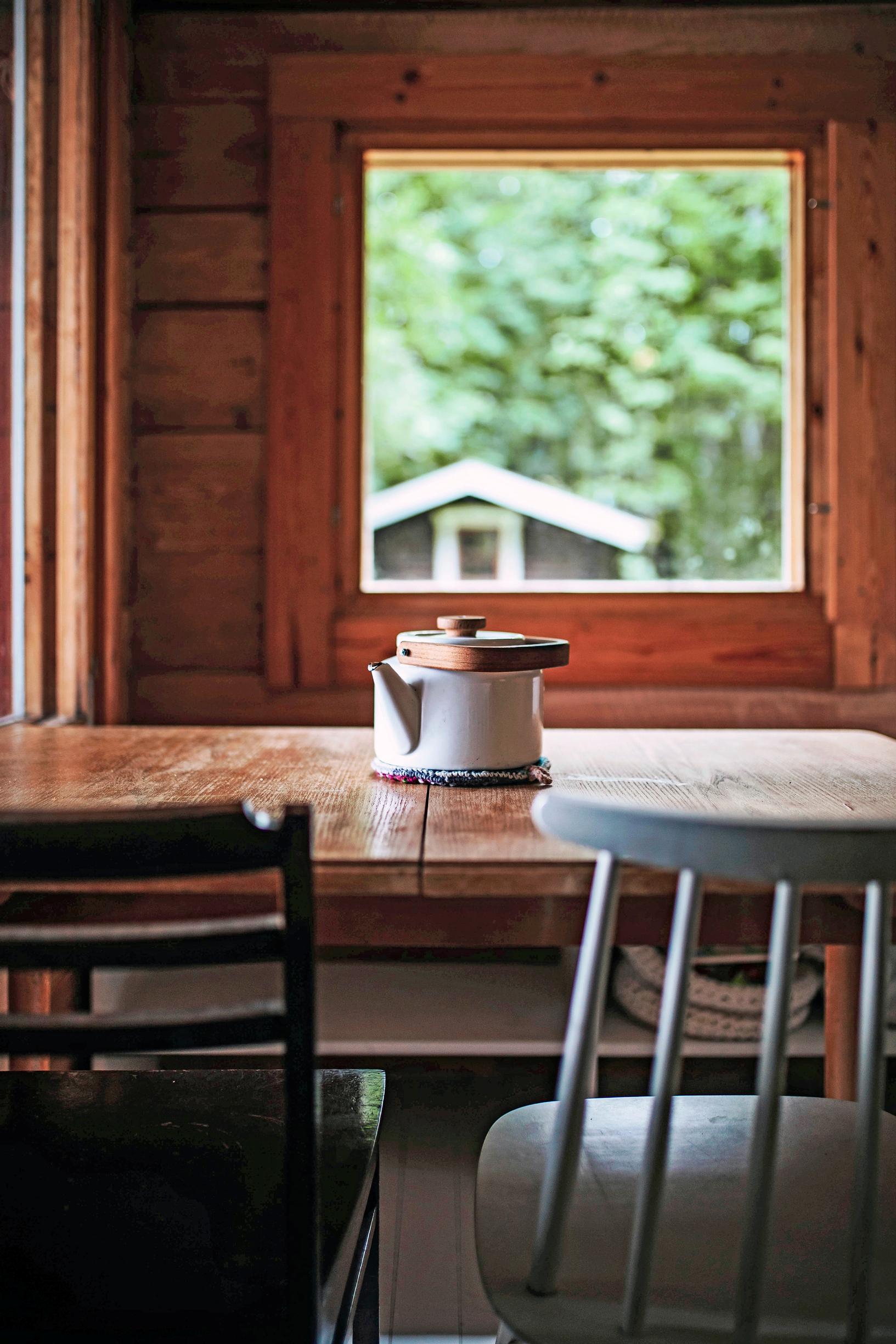 A coffee pot on the table in the cottage and two chairs.