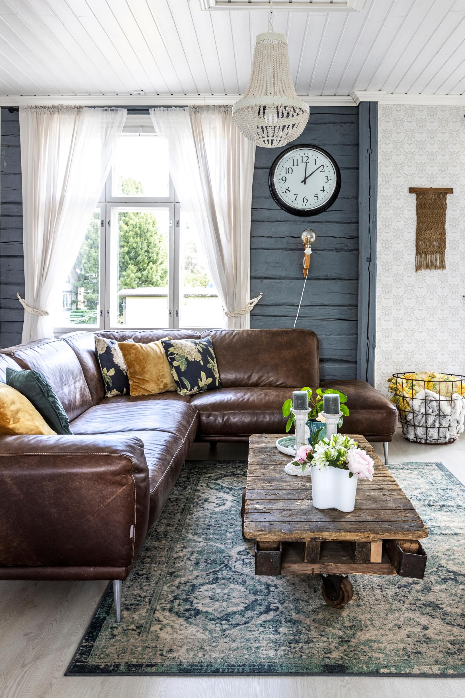 A log wall painted blue and a brown Natuzzi leather sofa