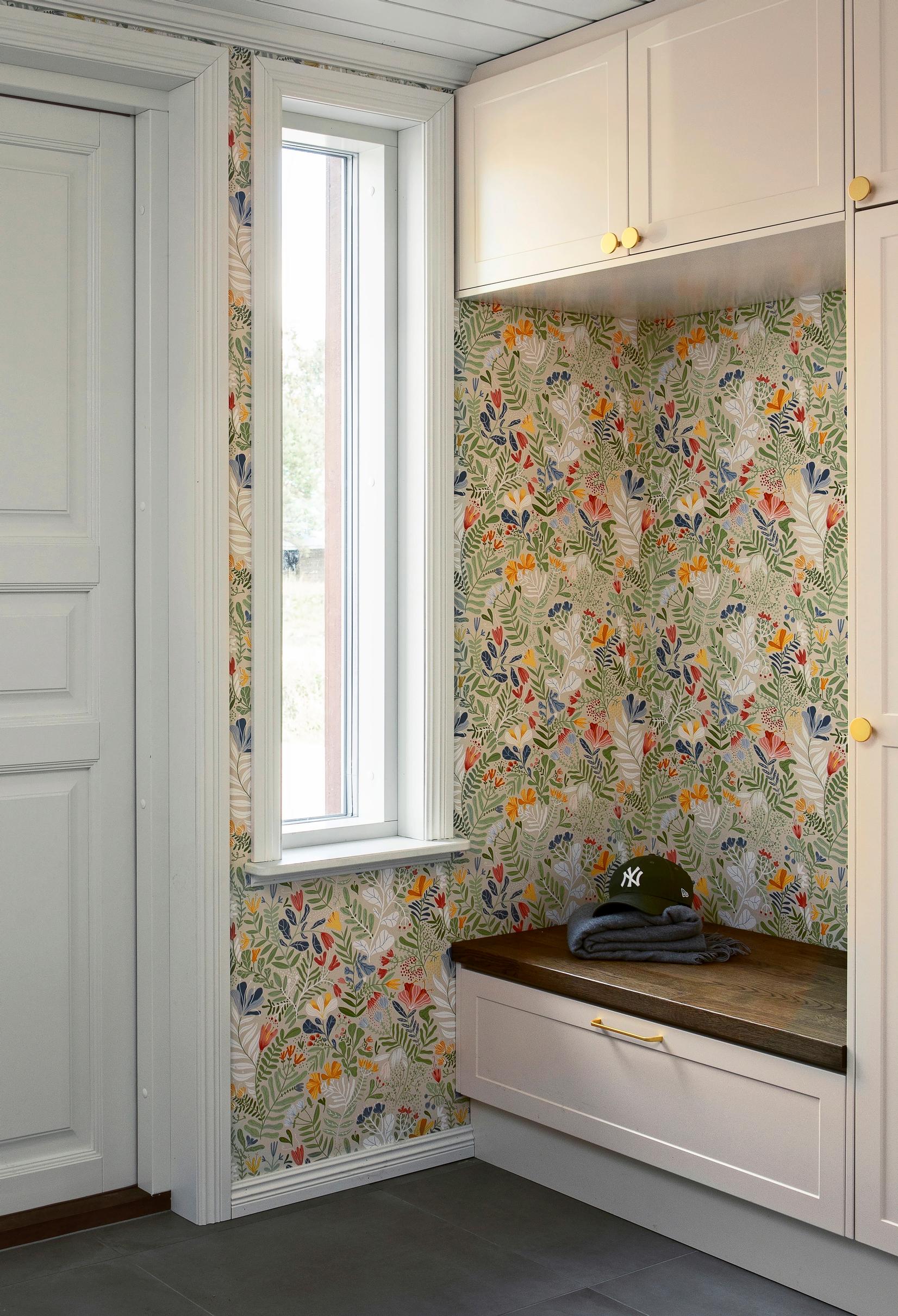 A wallpapered corner in the entryway with benches and cabinets
