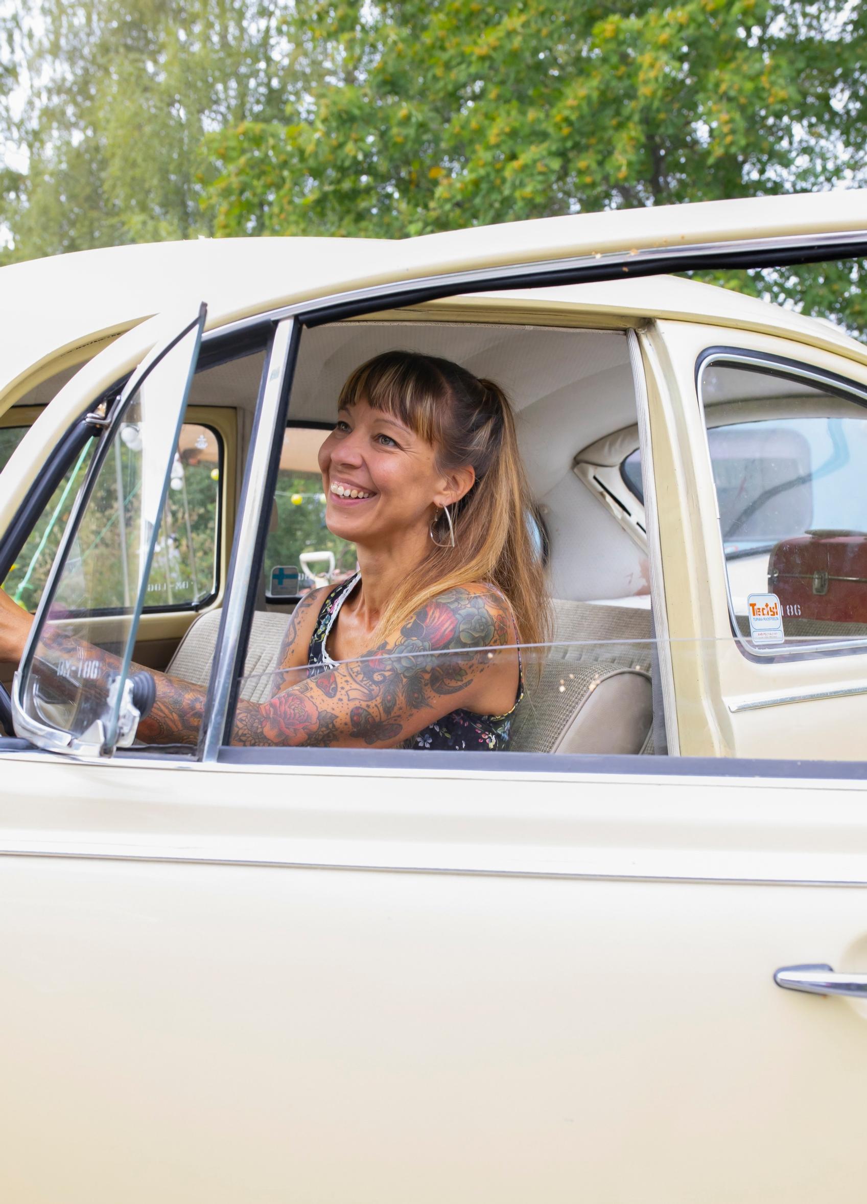 A woman laughing in a Beetle car