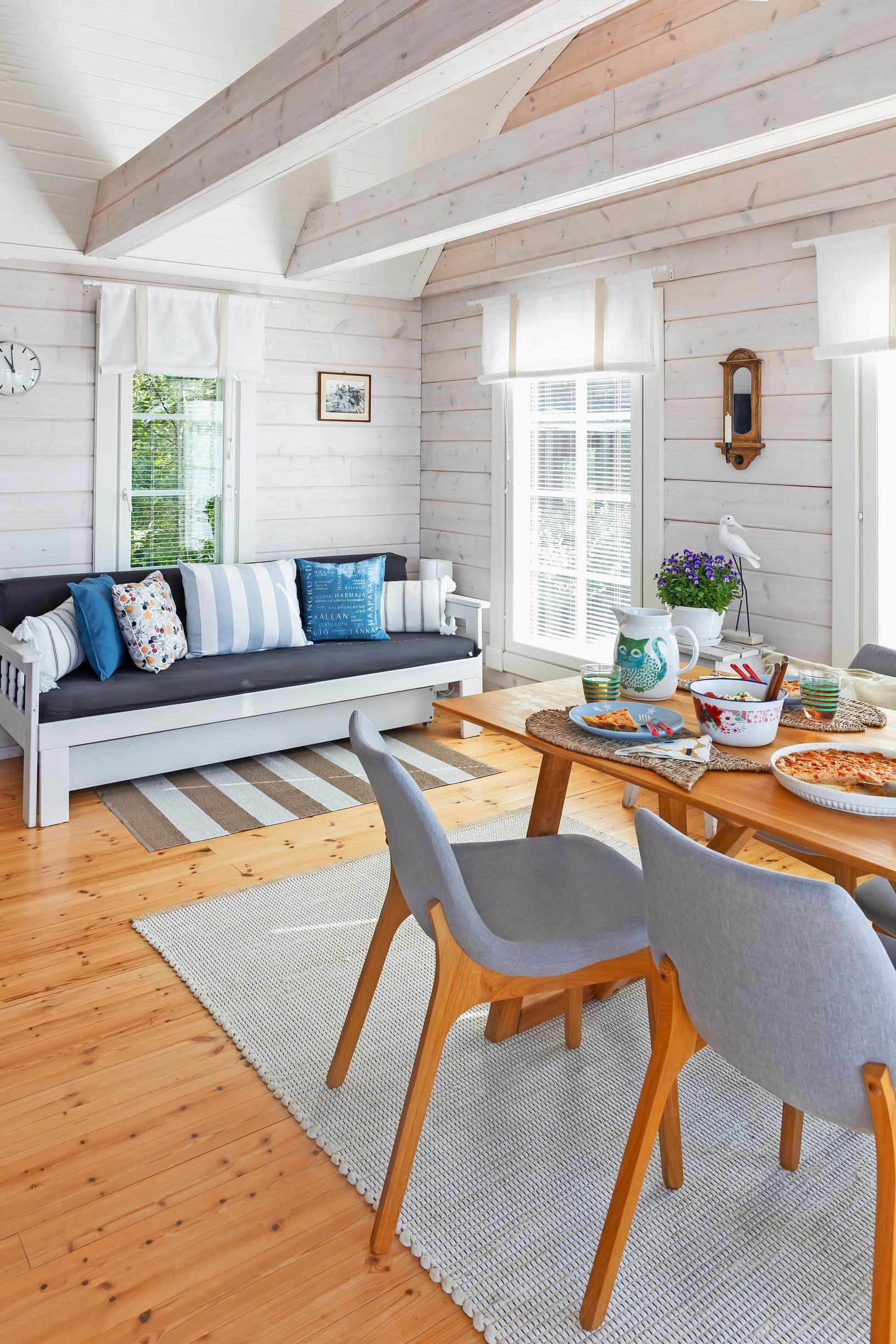 a sofa and a dining set in a light-colored log cottage