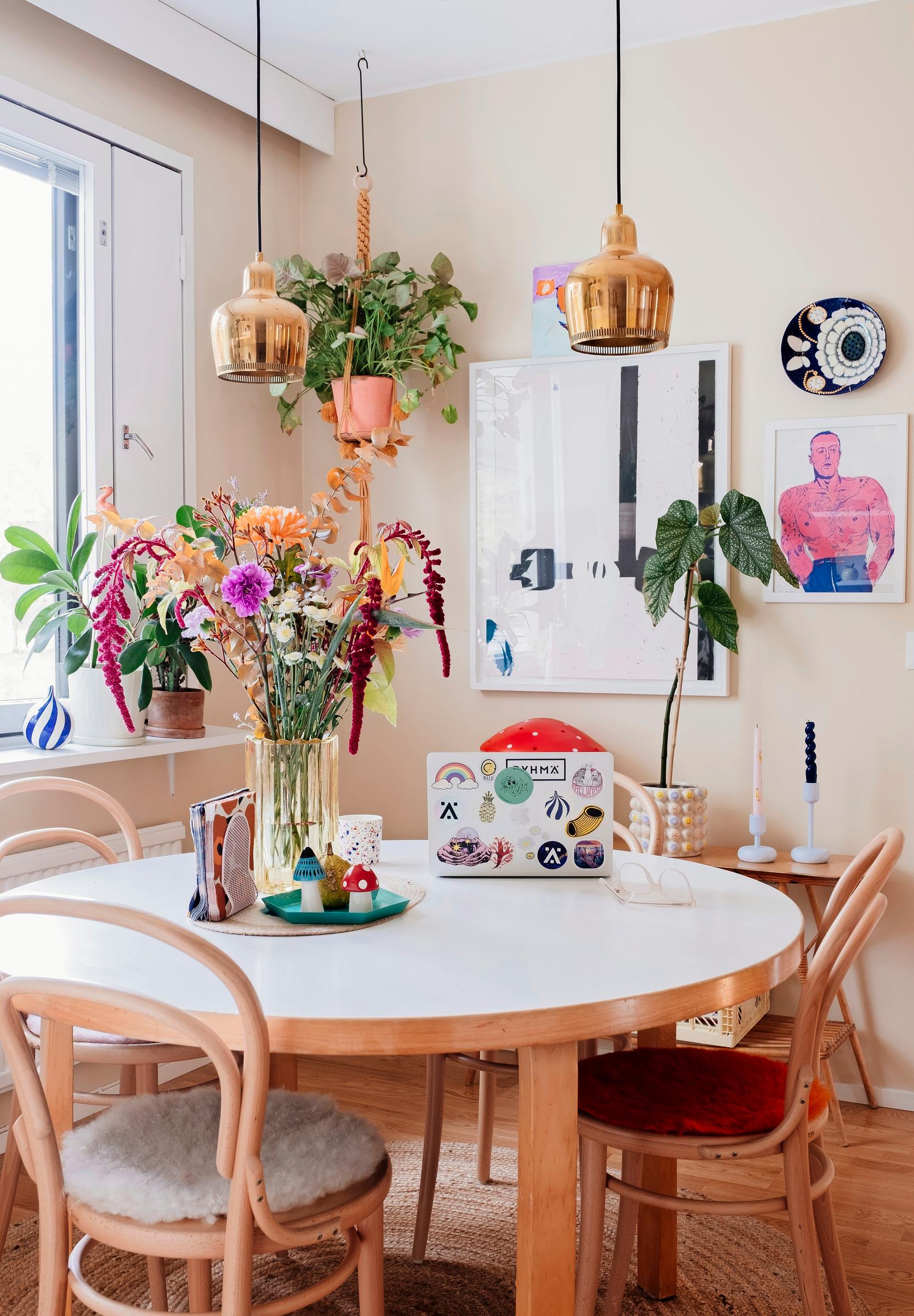 An Artek dining table, Ton chairs, and colorful flowers and artwork