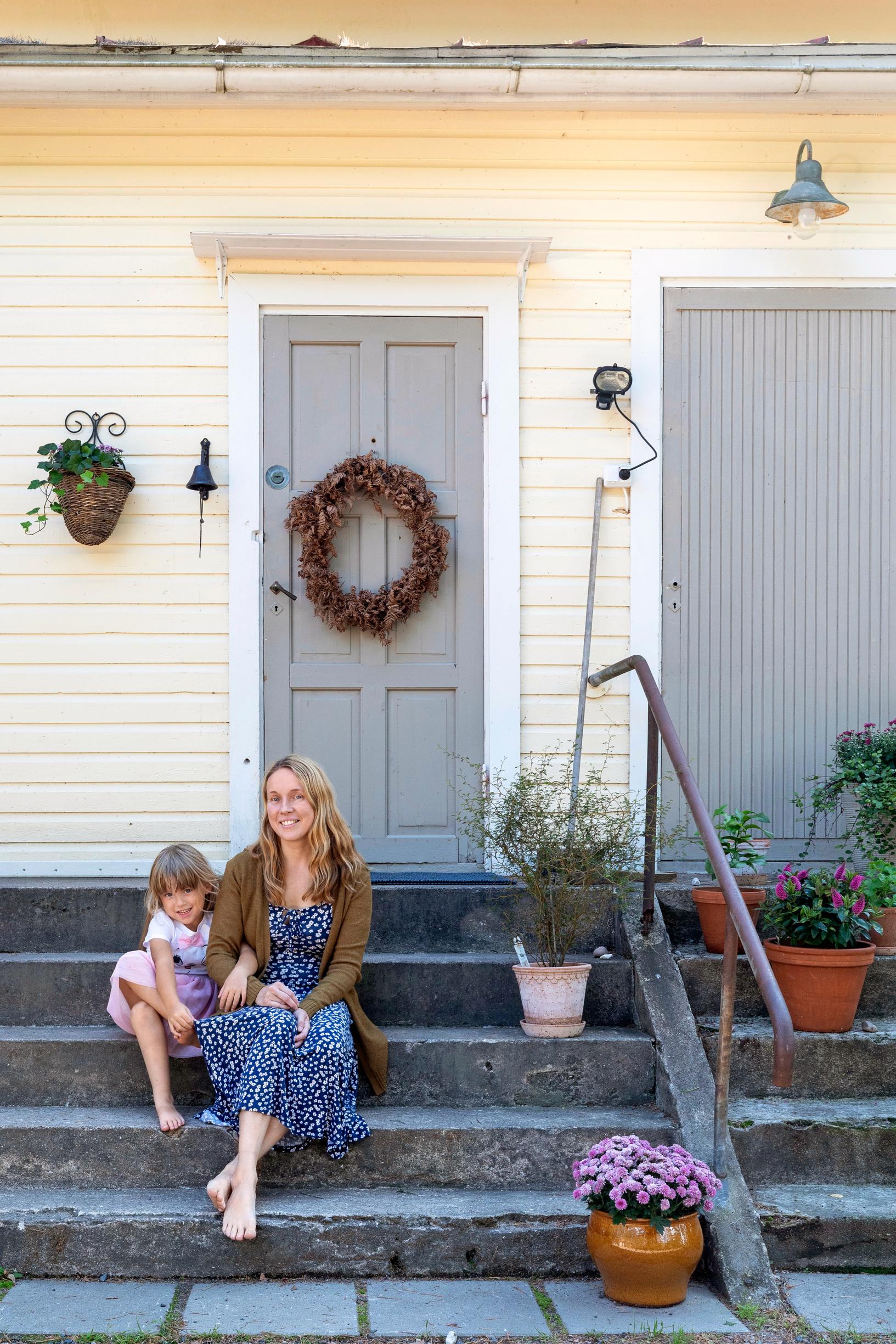 Hanna and her daughter on the steps by their home's entrance