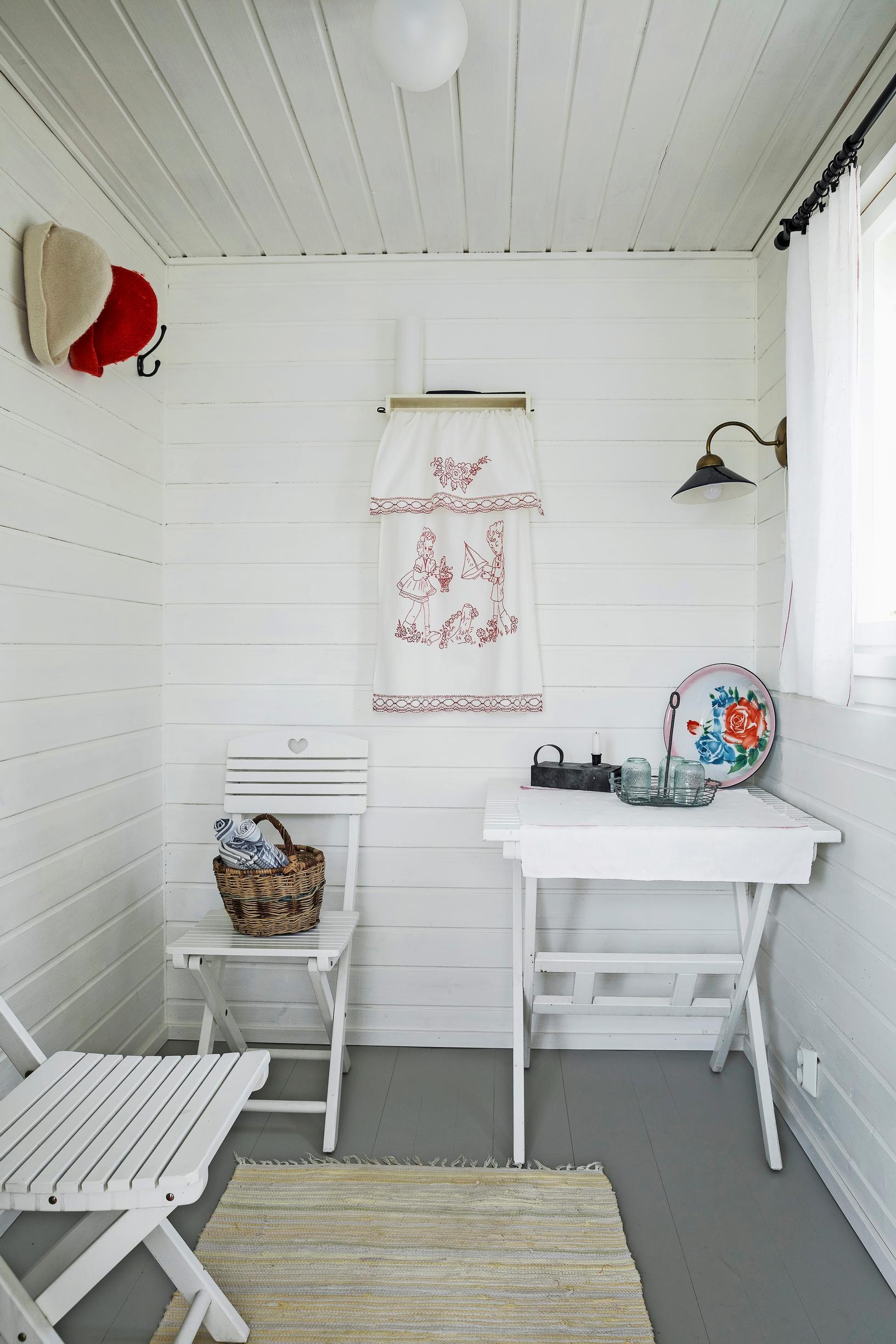 A narrow, white changing room with folding furniture