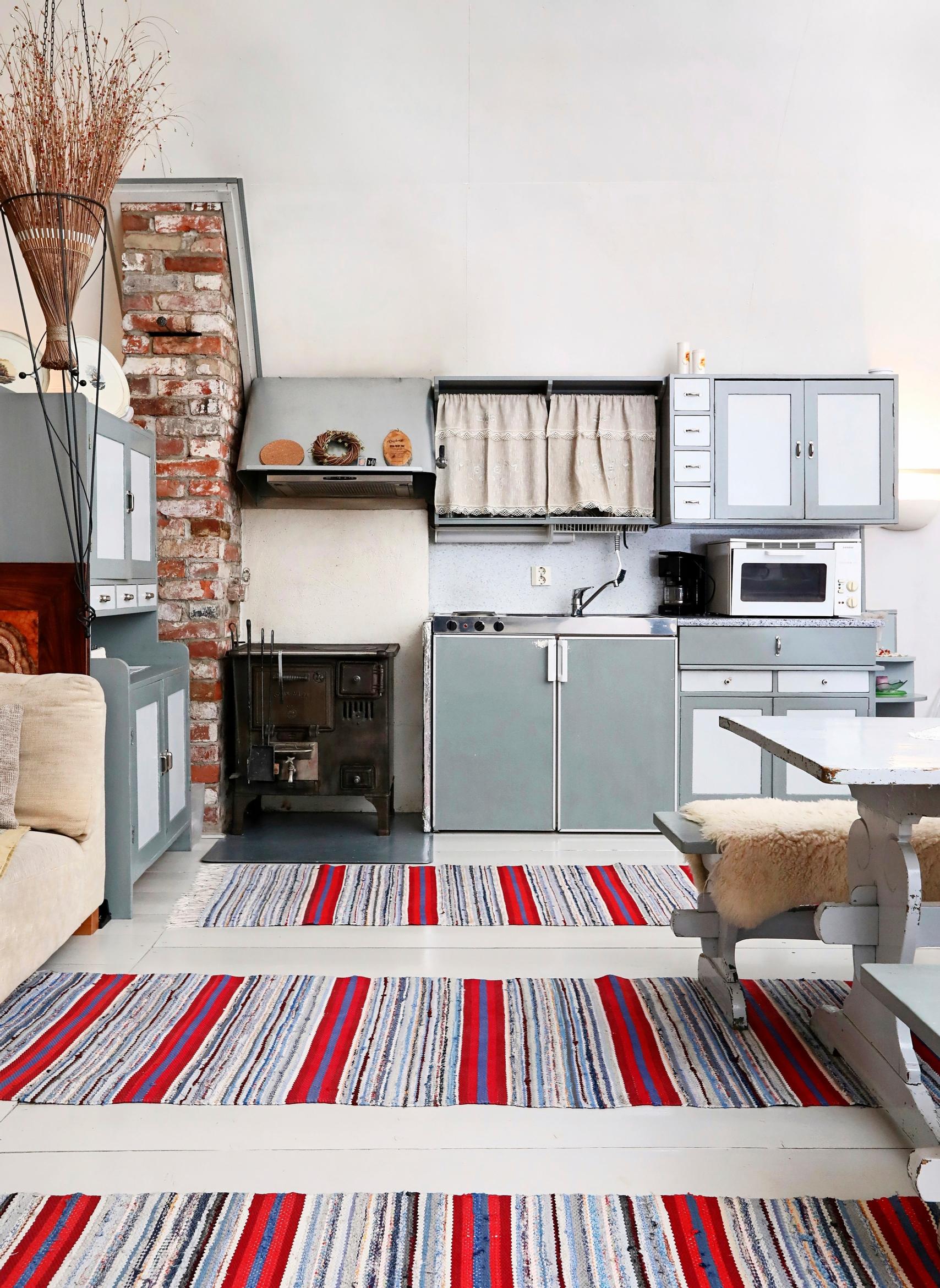 Gray kitchen cabinets and red-toned rag rugs