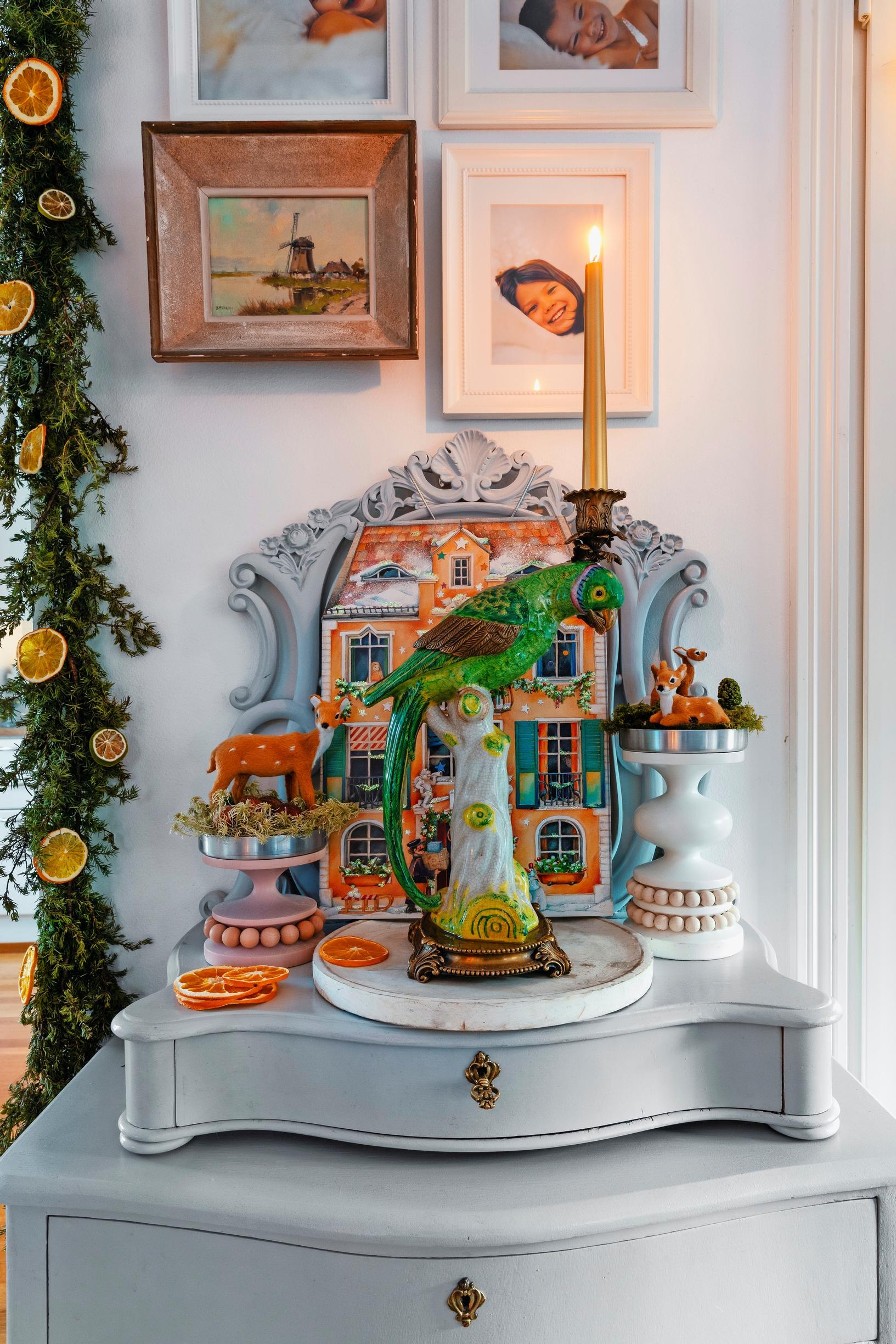 A Christmas arrangement topped by a large parrot-shaped candleholder.