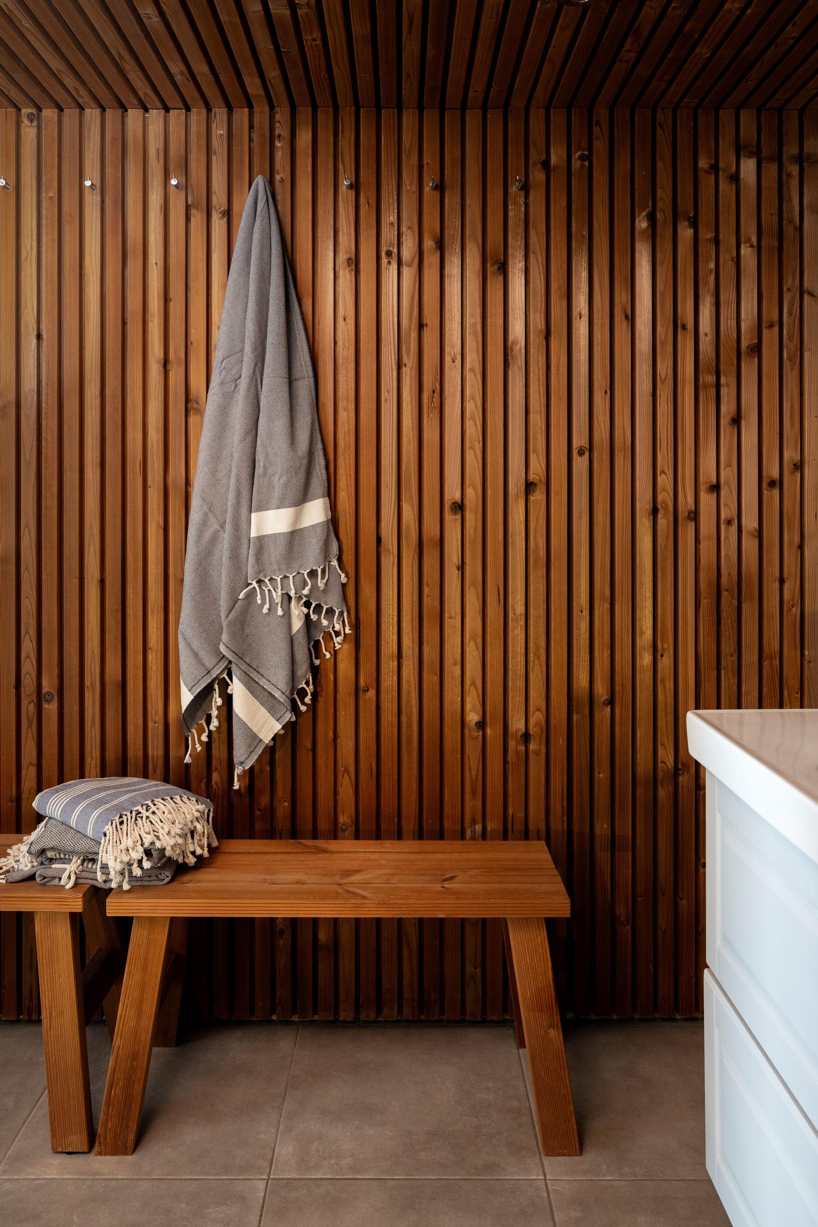The bathroom has dark wood paneling and small wooden benches