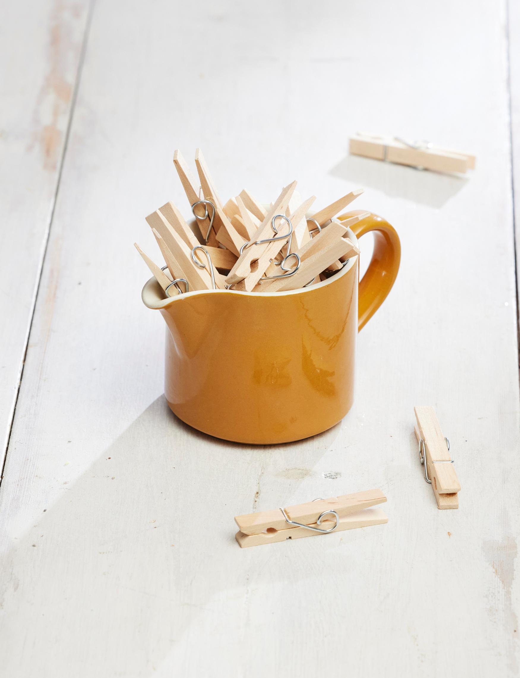 An old Arabia milk pitcher holding wooden clothespins.