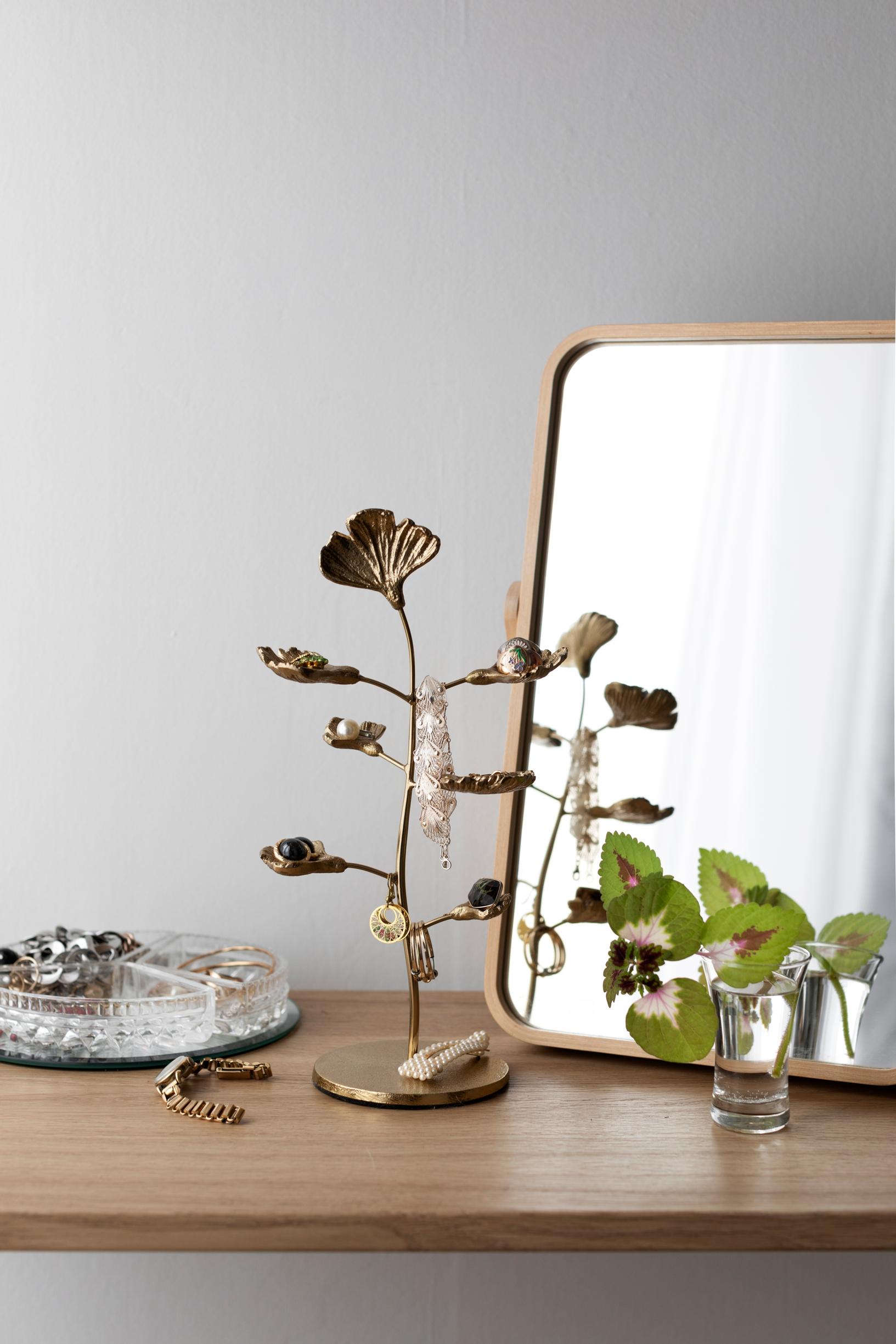 A jewelry stand and a table mirror on the makeup table