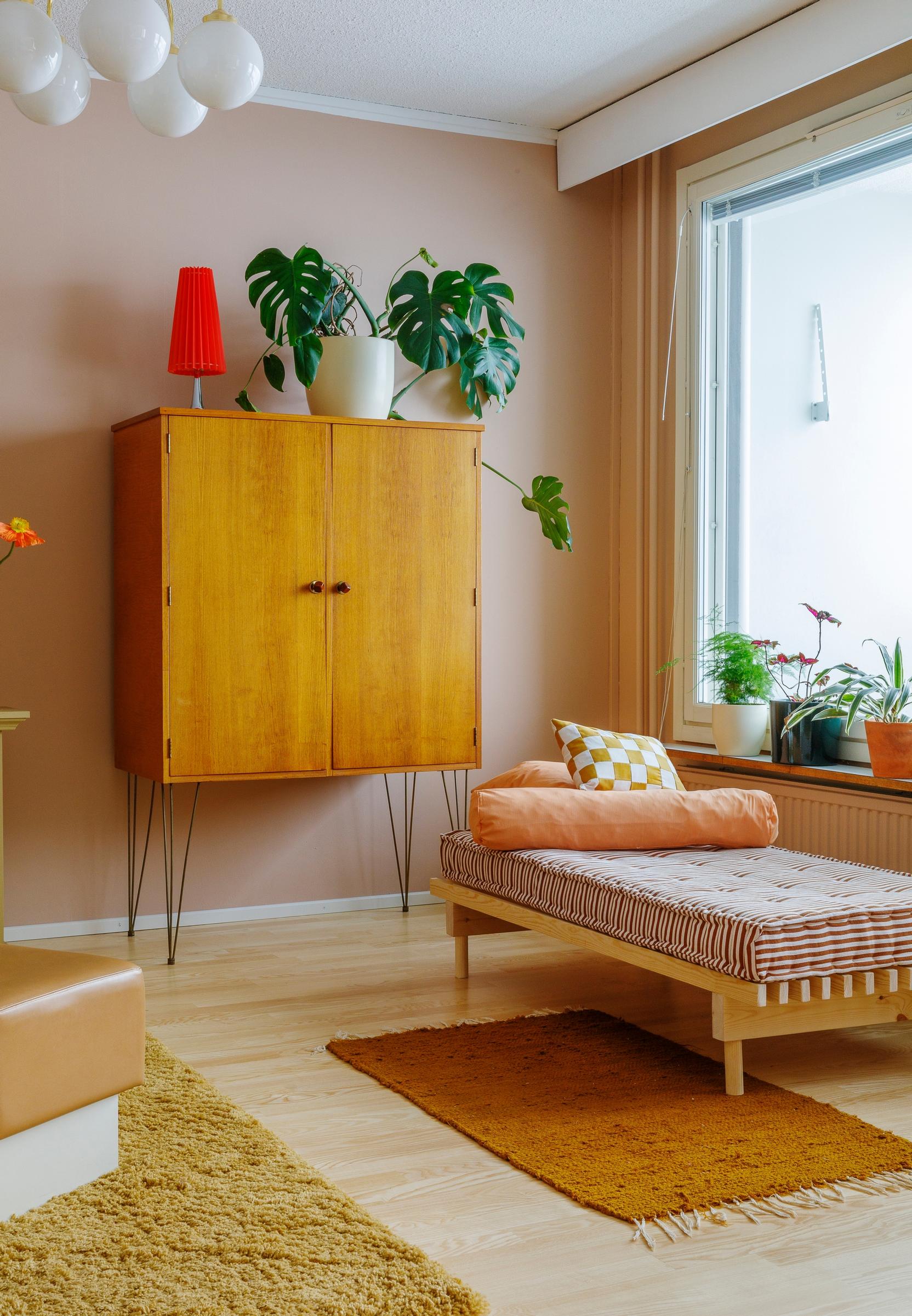 Arranging plants indoors: monstera, old dresser, and daybed in front of the window