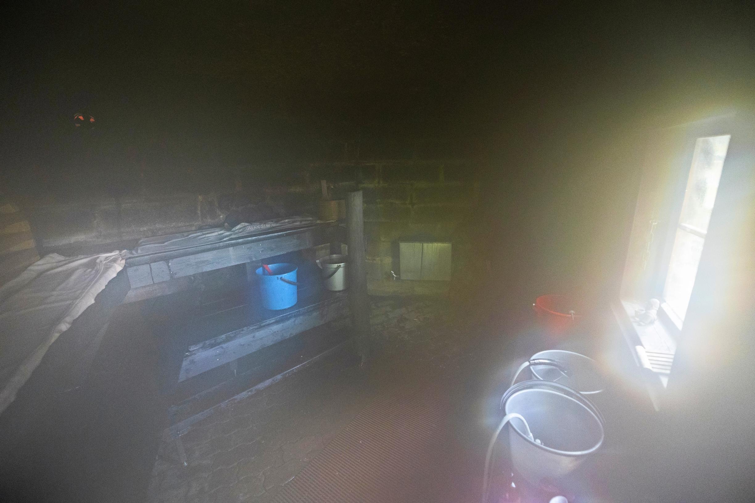The smoke sauna’s misty ambiance, with buckets and benches, and a window on the right