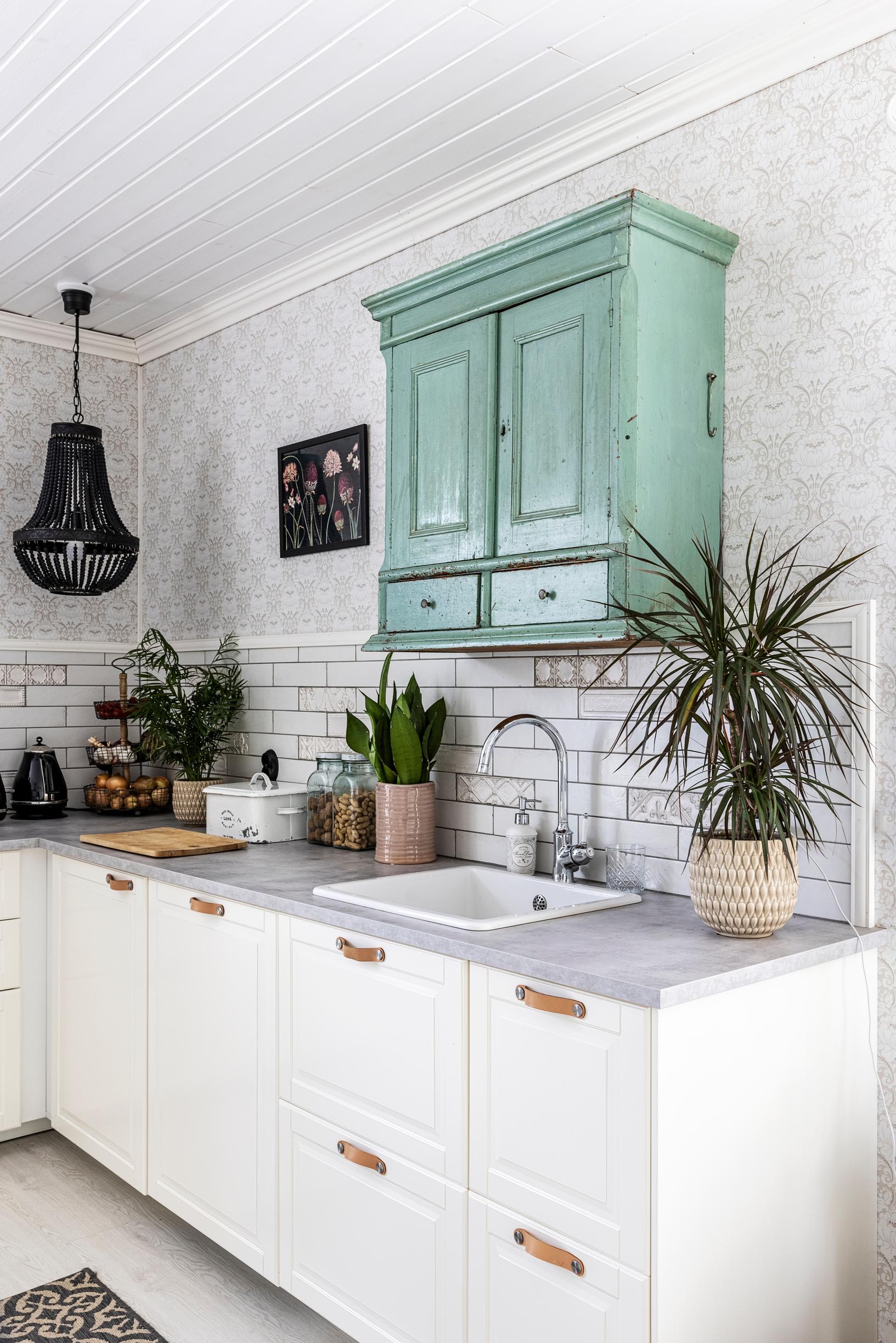 An old small cabinet mounted on the wall above the sink in a modern kitchen.