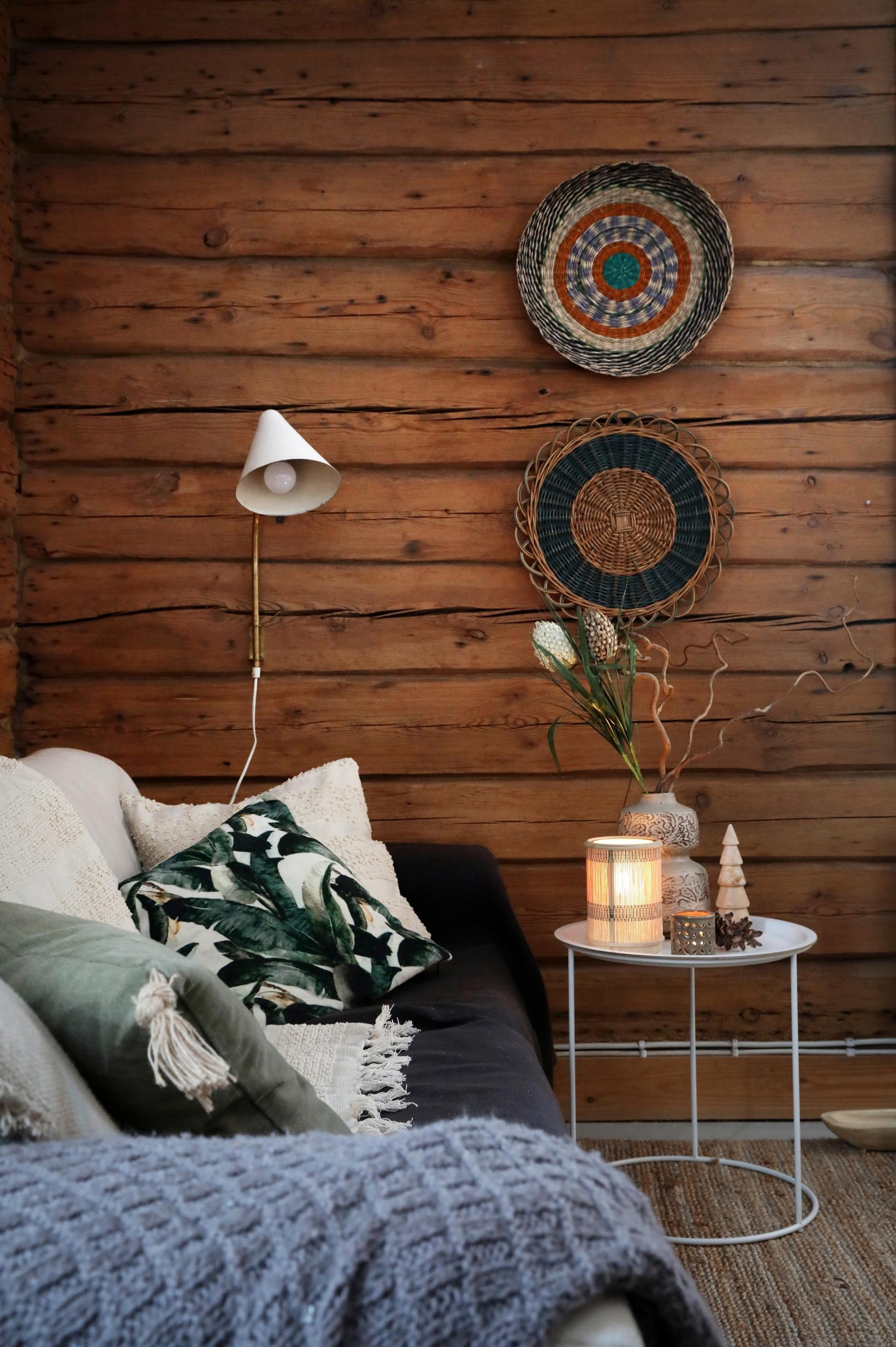 on the log wall, decorative plates and a wall lamp; next to the sofa, pillows and a coffee table with decor items on top.