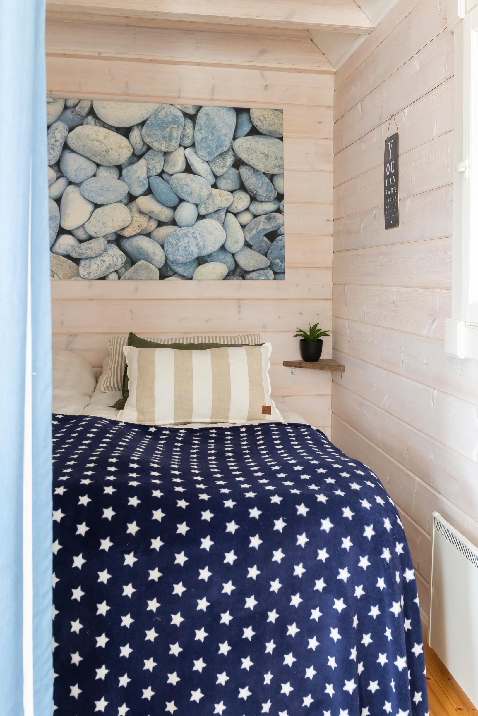 a bedroom with a bed and a stone-themed poster