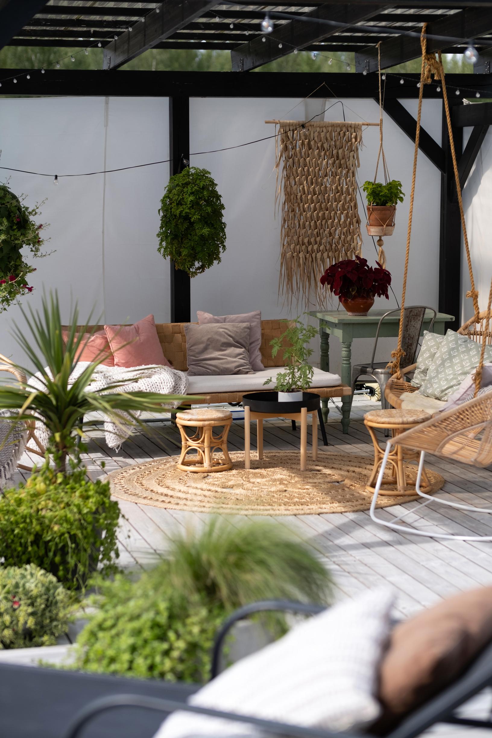 Rattan furniture and hanging plants beneath the pergola