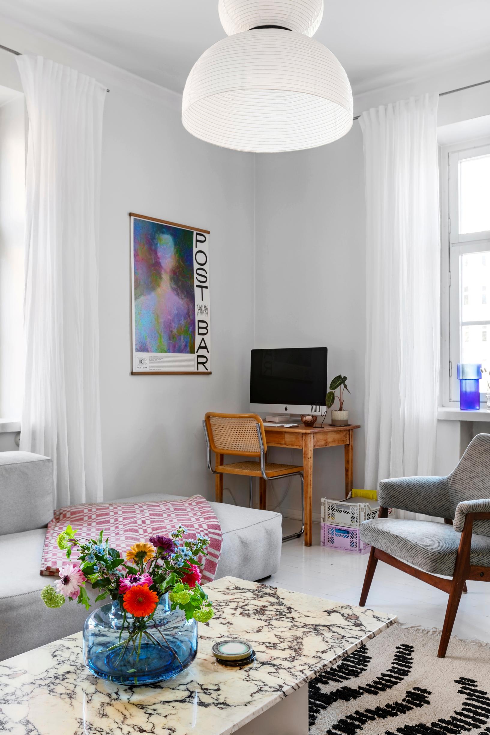 A living room with a workspace in the corner