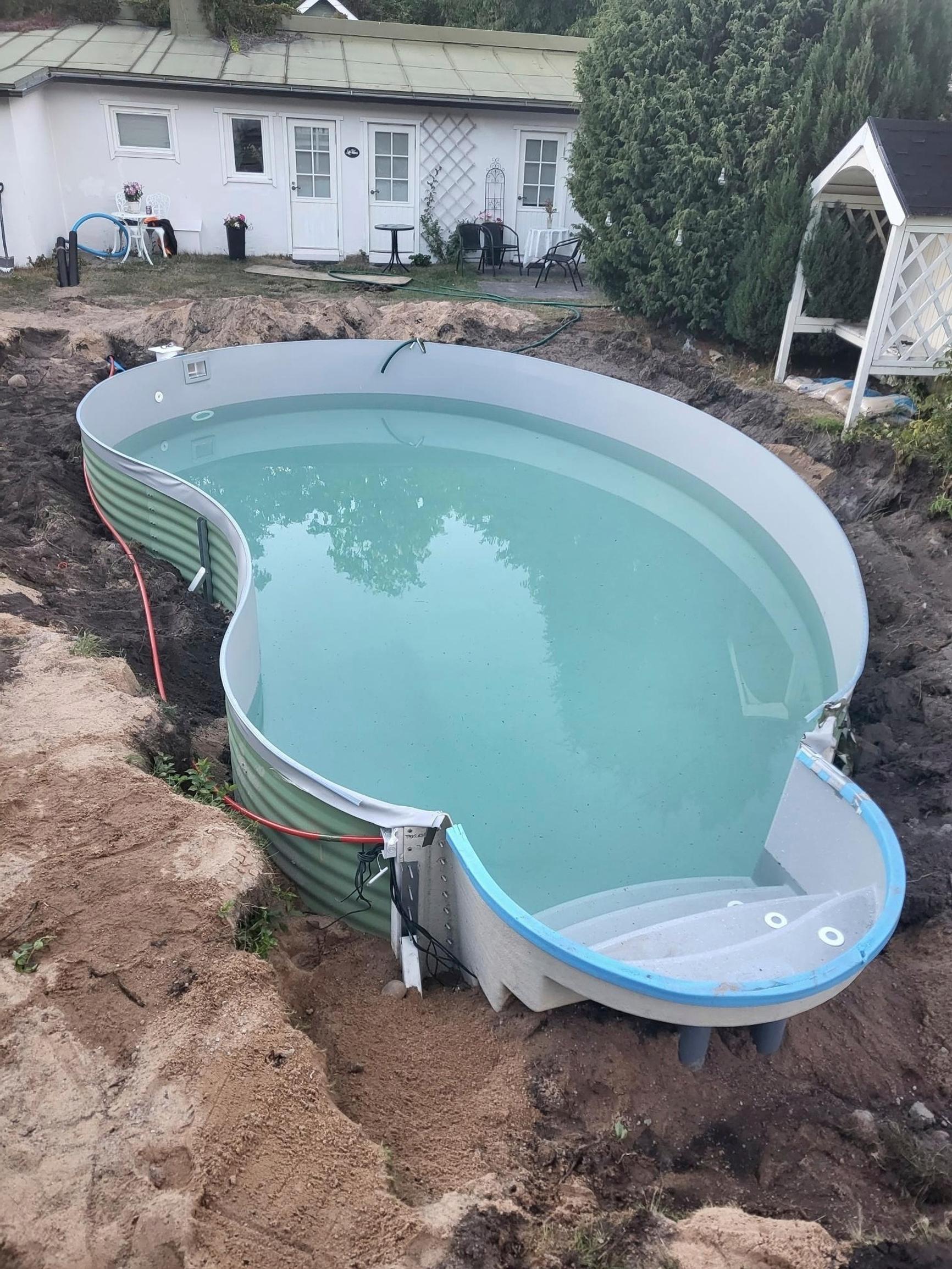 The pool, filled with water, sits in the still-unfinished excavation.