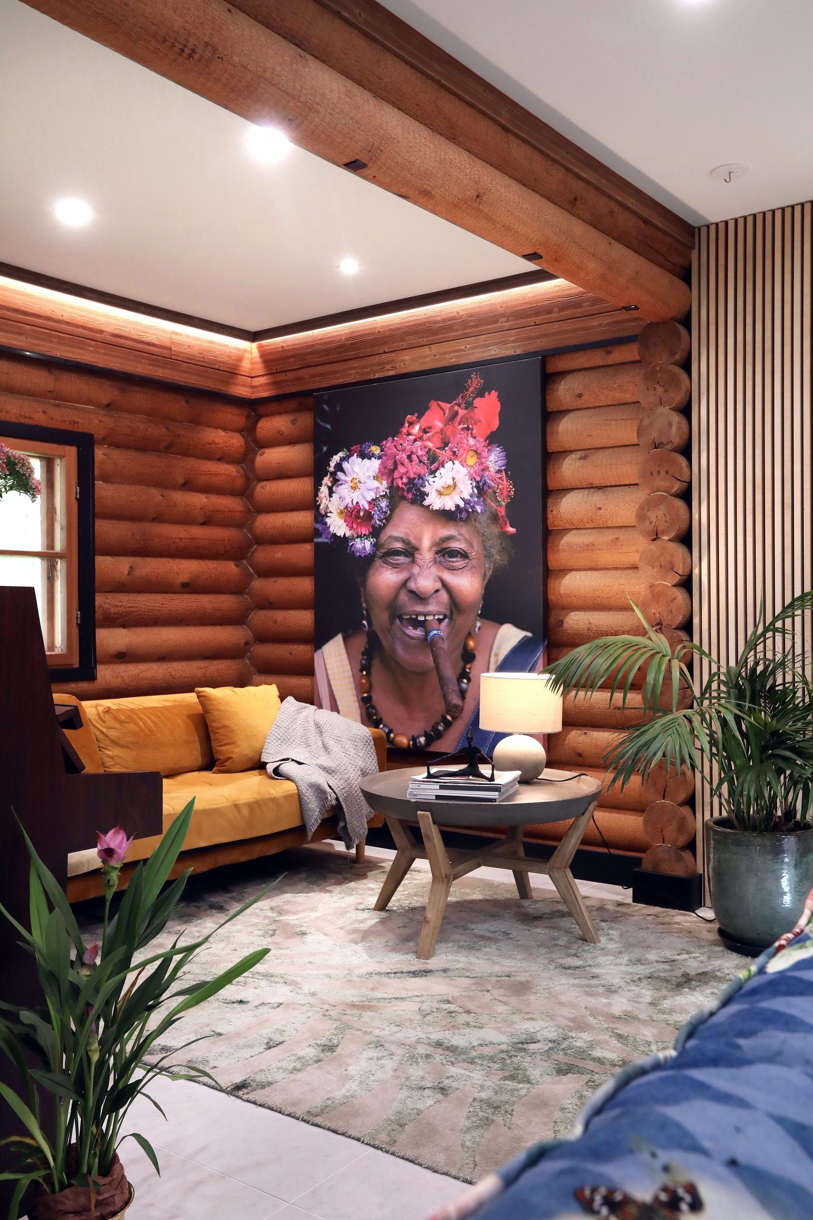 On the log house wall, there’s a large painting of a laughing woman.
