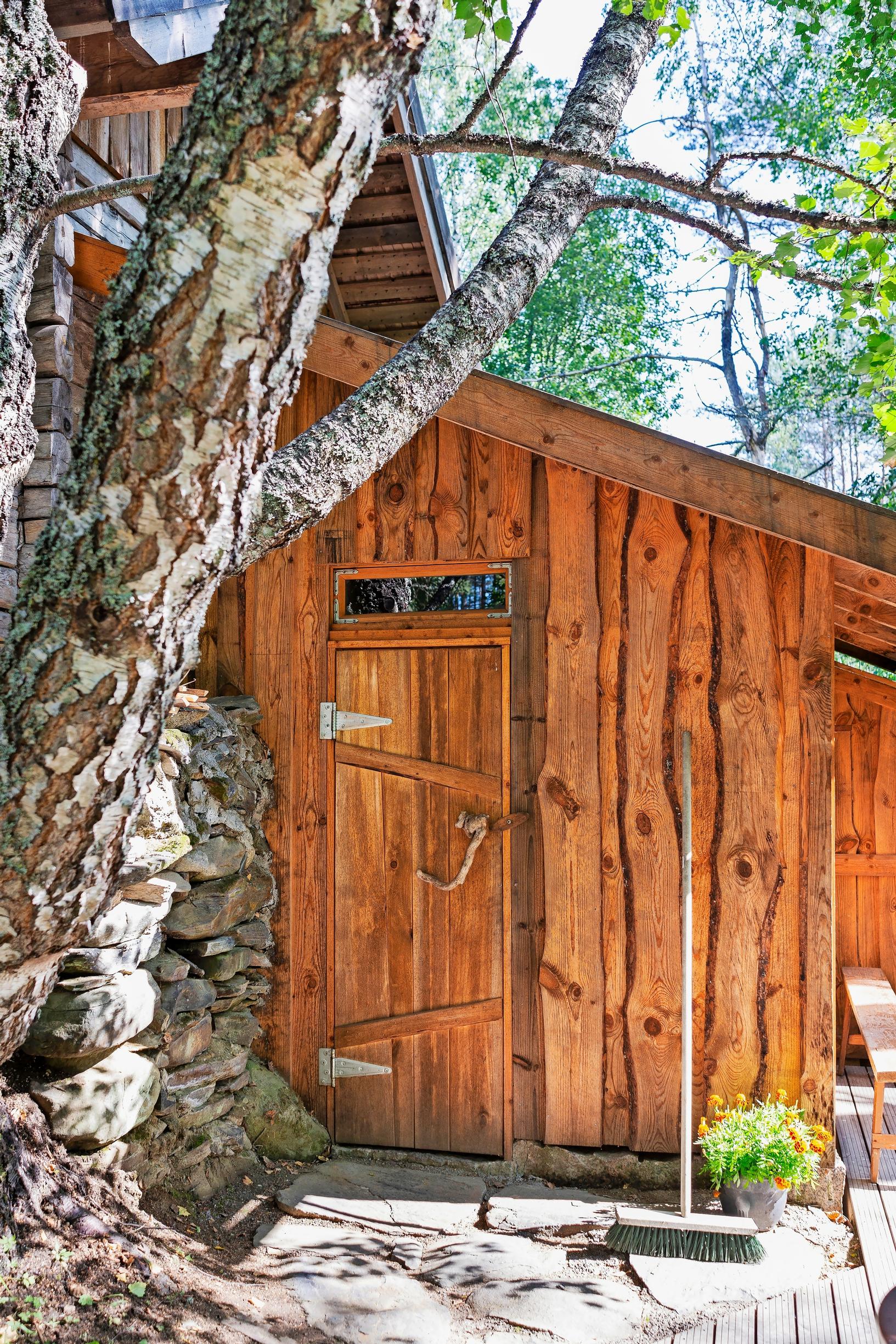 Unique saunas: A smoke sauna built next to a stone wall, embraced by two trees