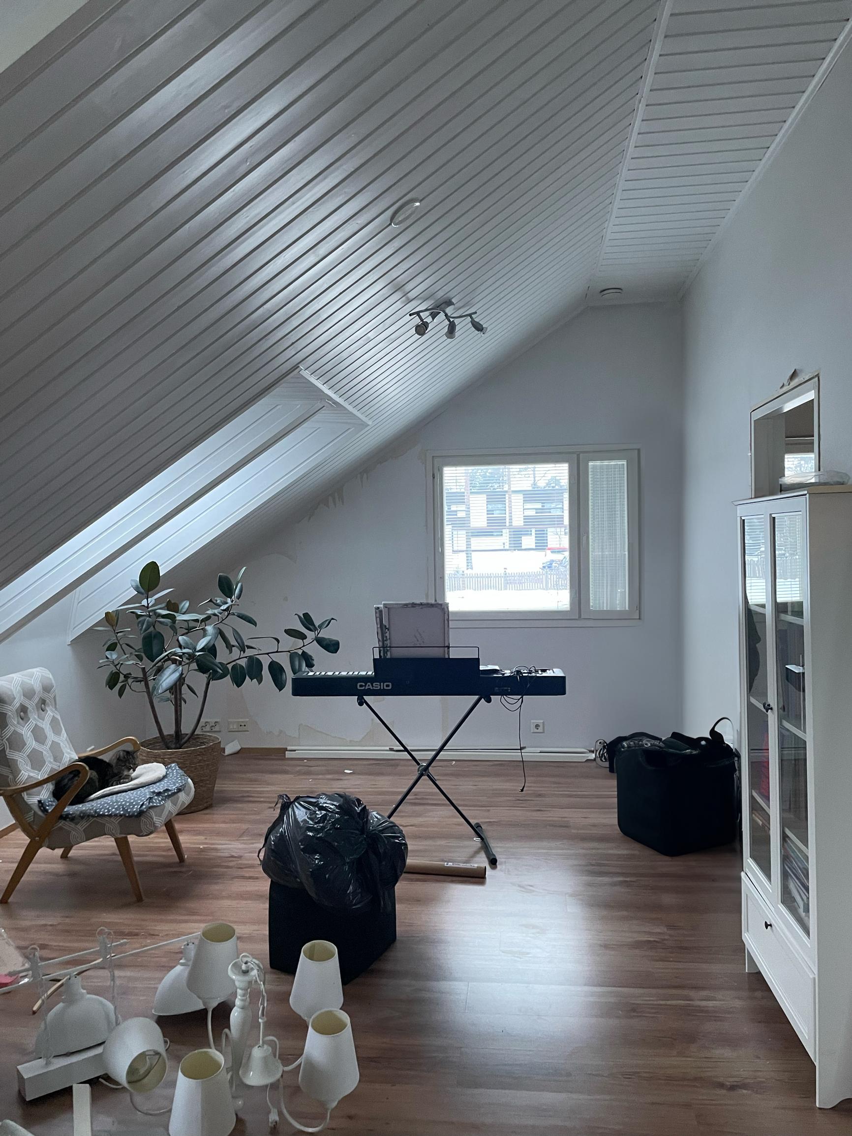 The space has white walls and a reddish-brown floor. There are a few pieces of furniture scattered here and there.