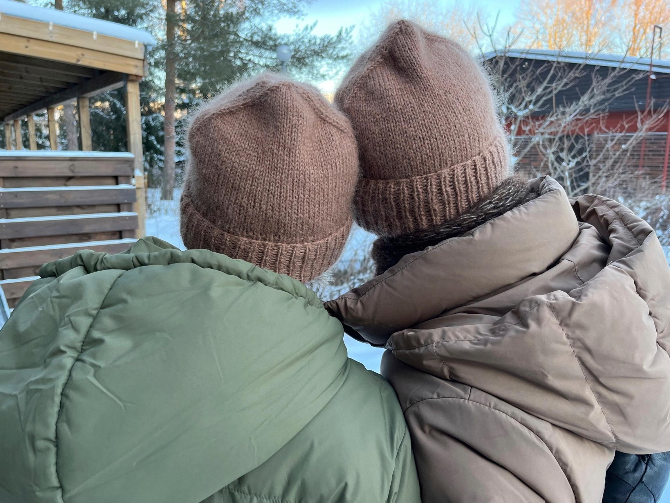 Wearing matching brown hats, leaning against each other