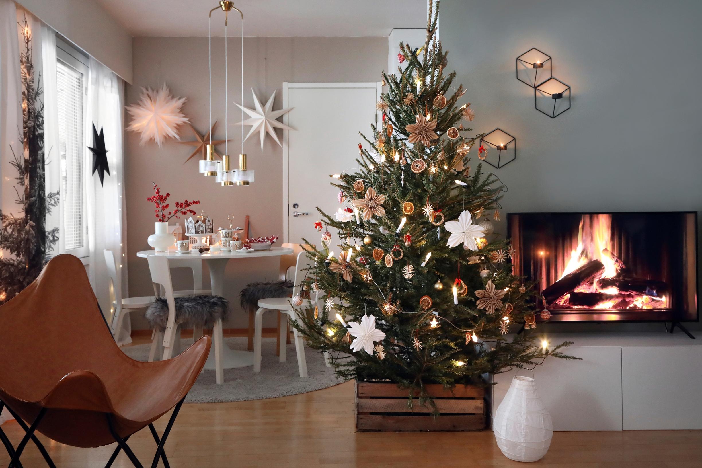 A living room with a Christmas tree and a fireplace on the TV