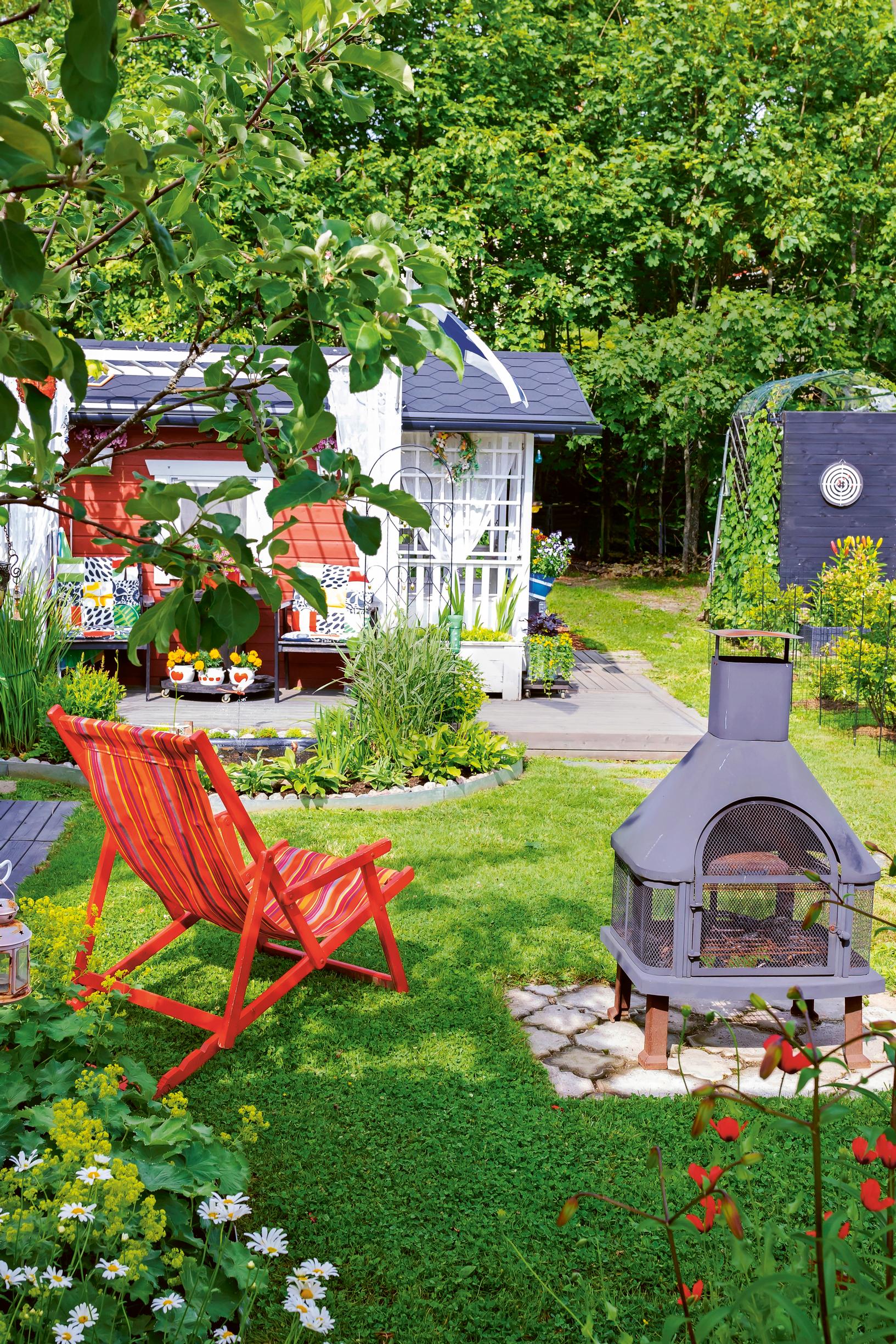 a bright red deck chair on a green lawn, a playhouse, flower beds, and a fireplace