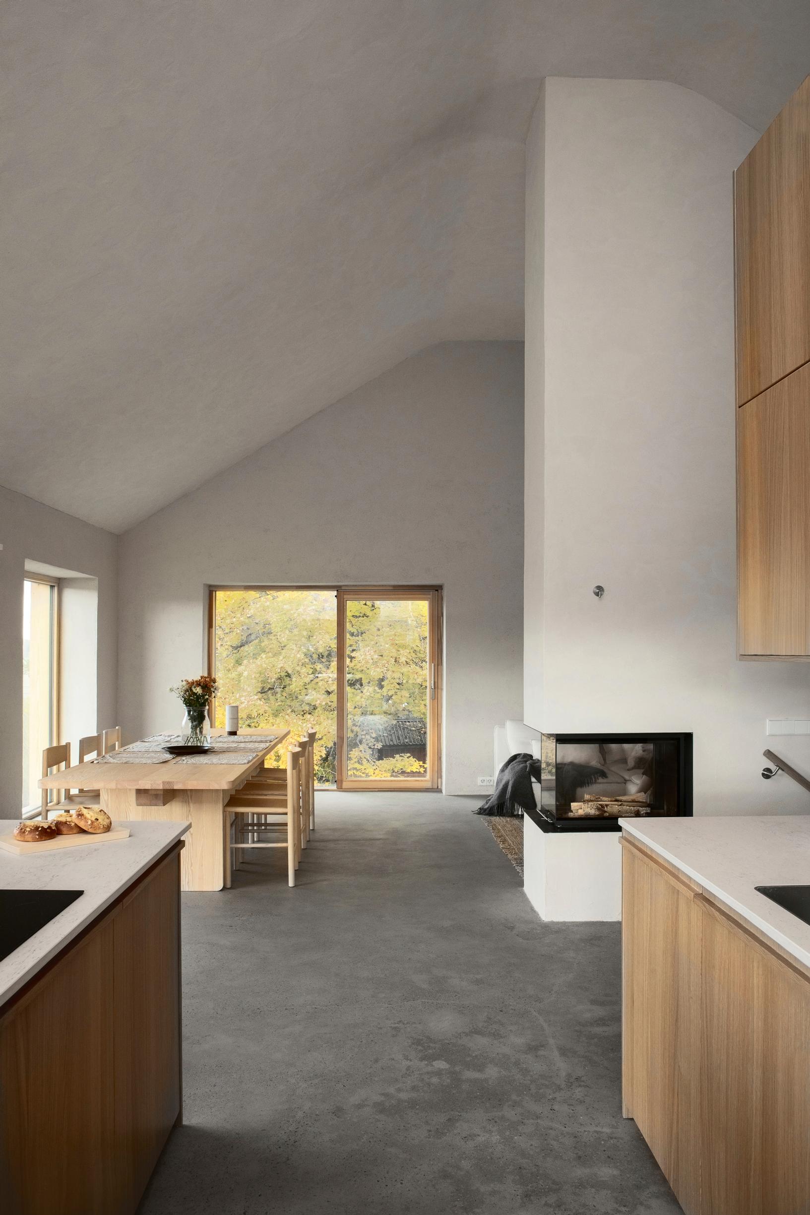 Open-plan kitchen with natural cement floor and clay-plastered walls
