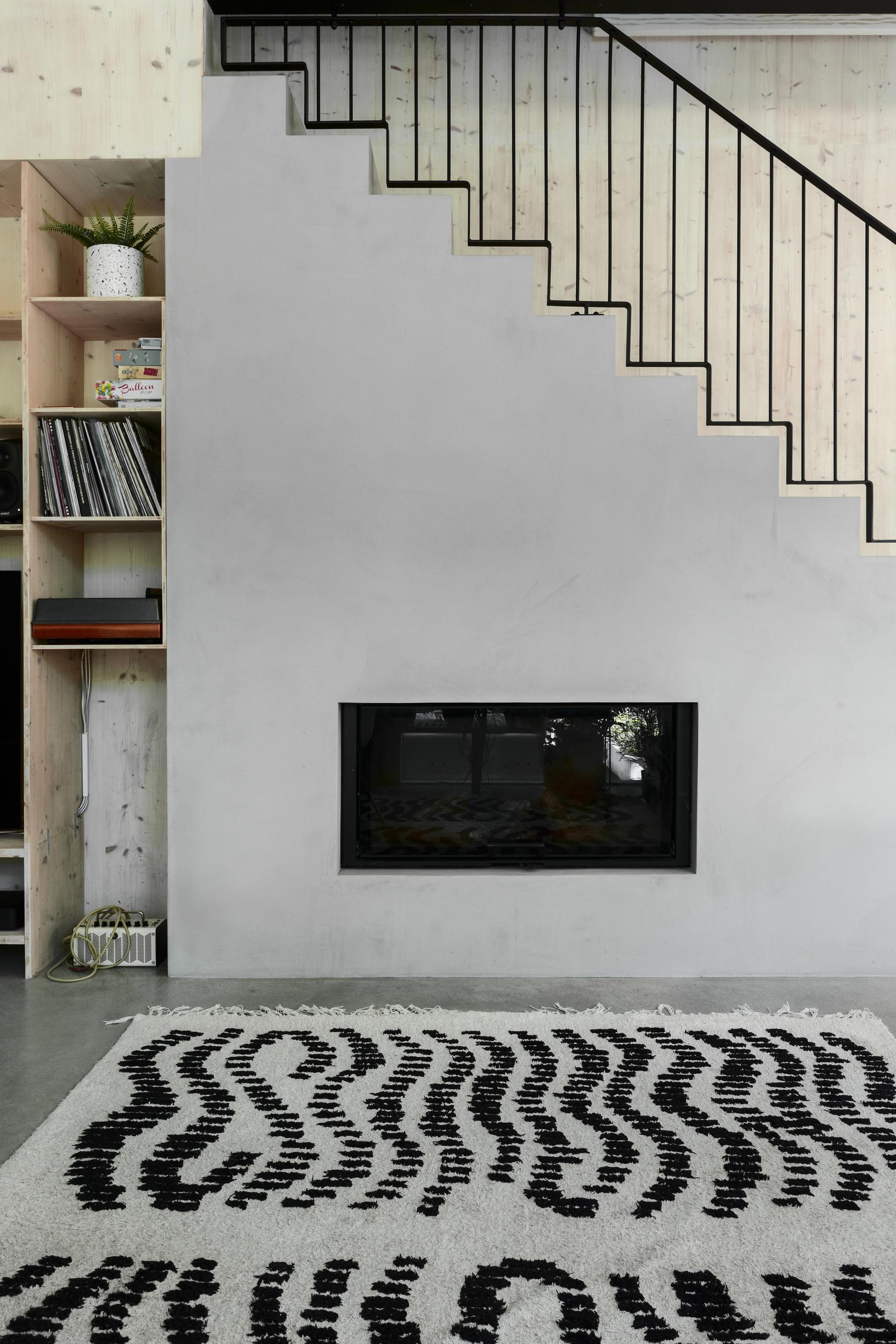 A fireplace sits within the staircase. The staircase has a metal spindle railing.