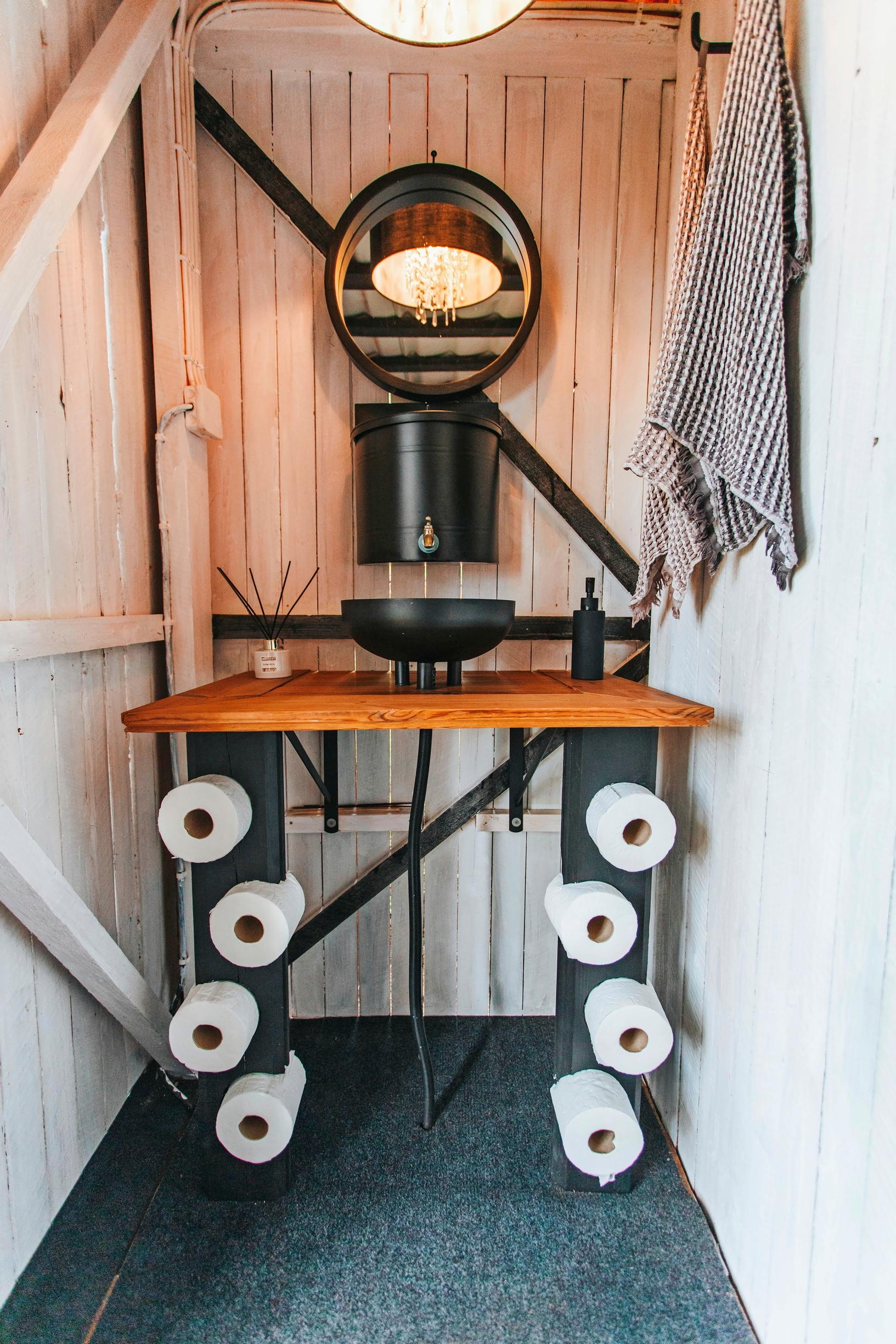The outhouse’s hand-washing area, where the logs have been crafted to hold toilet paper rolls