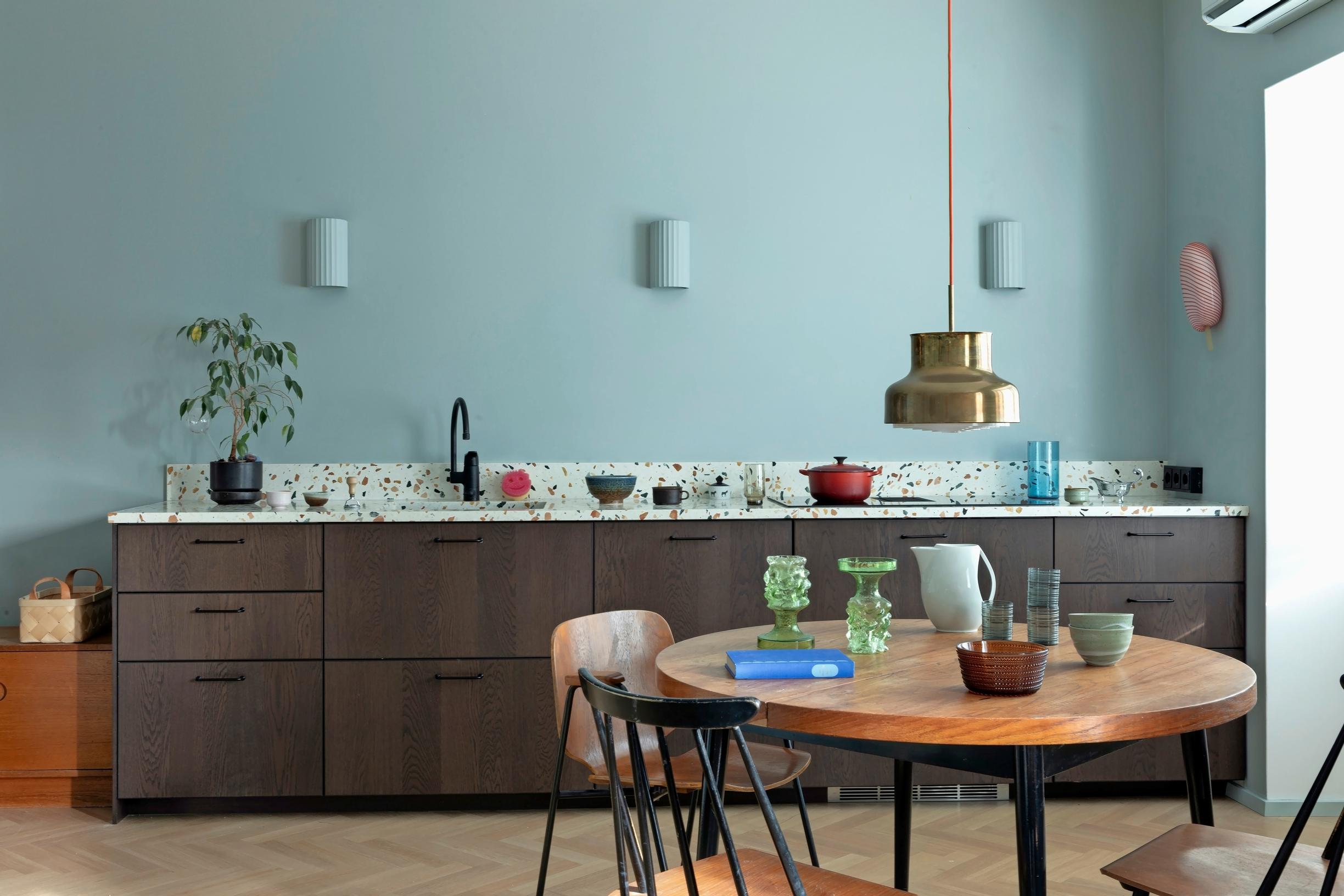 In a kitchen without upper cabinets, dark base cabinets and a terrazzo countertop