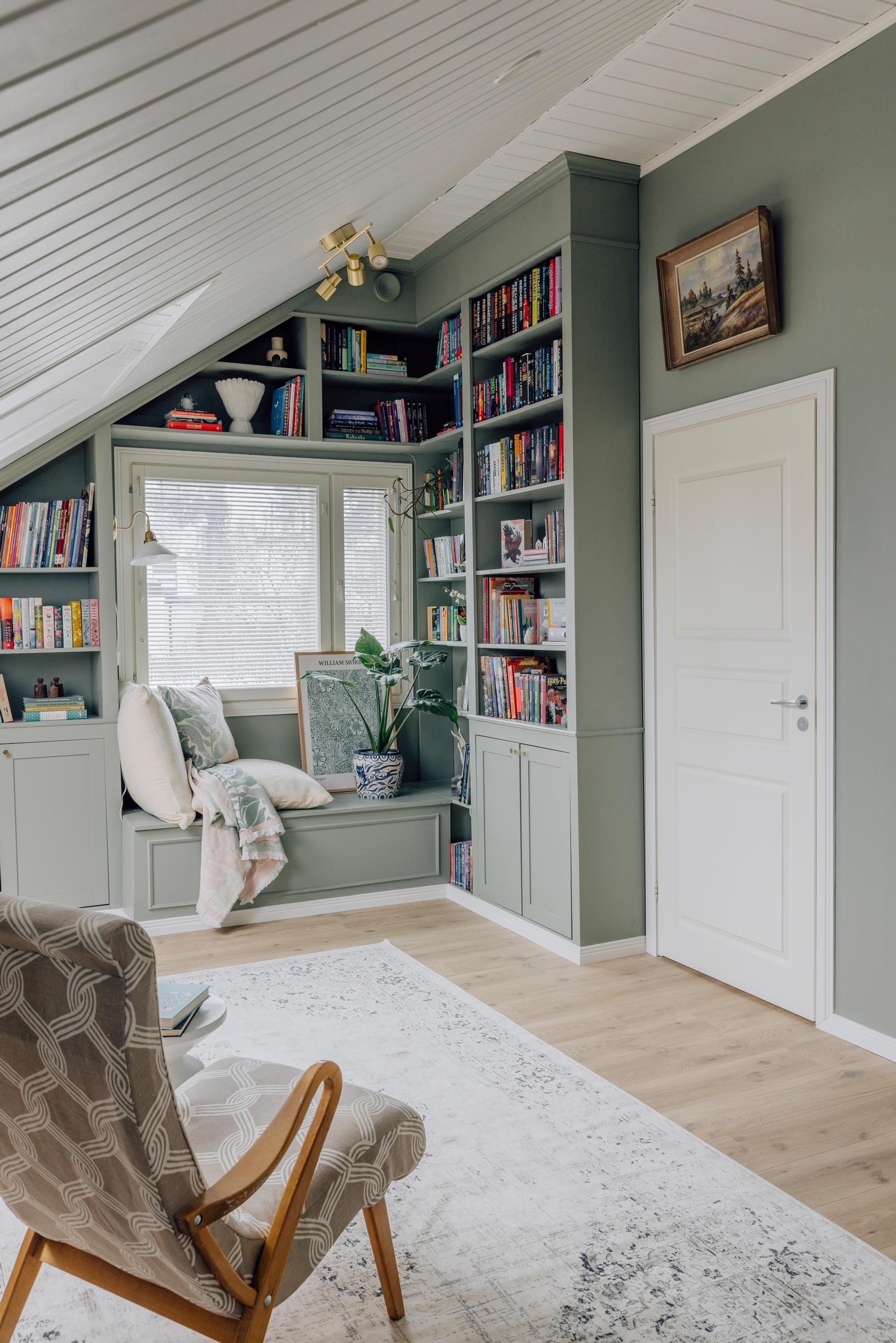 There is a full-height bookcase next to the bedroom door. On the adjacent sloped wall, shelves surround the window.