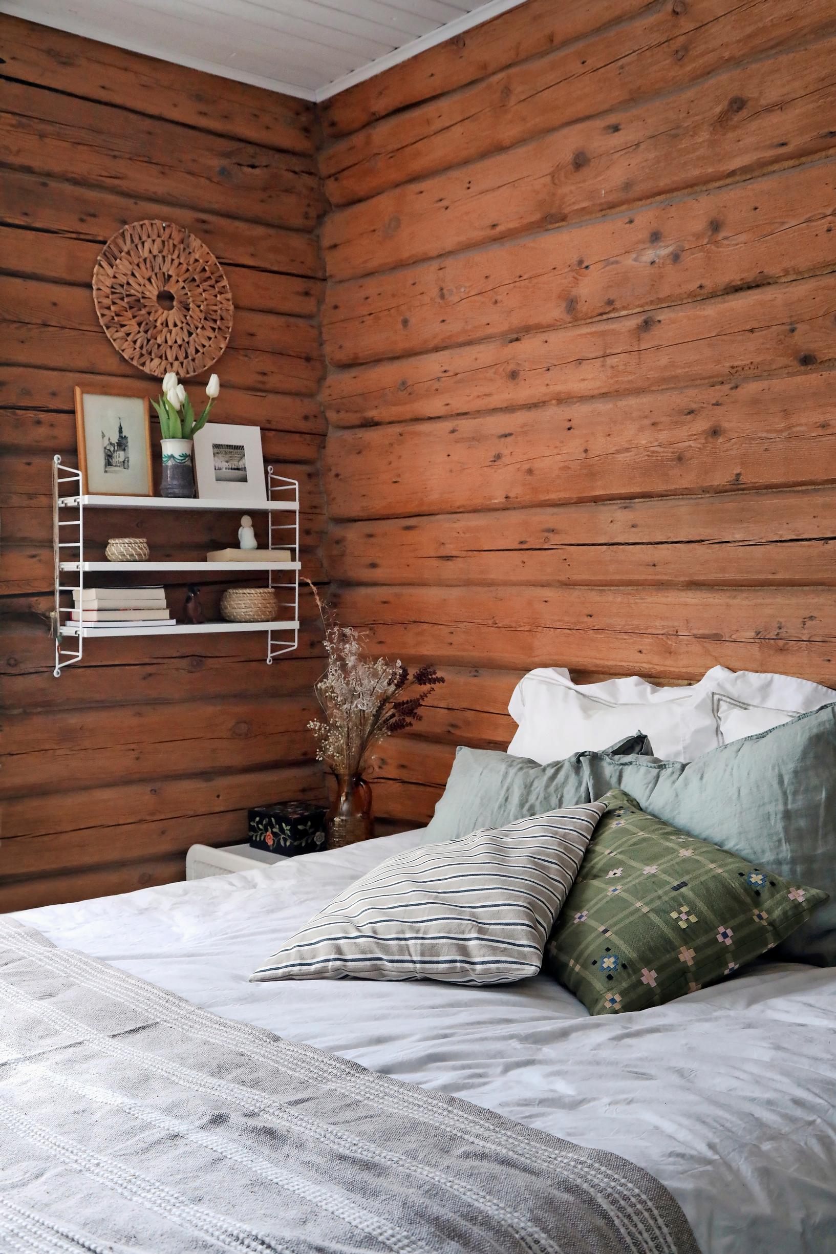 In Ulla Parviainen’s log cabin bedroom, a white String shelf is mounted on the wall.