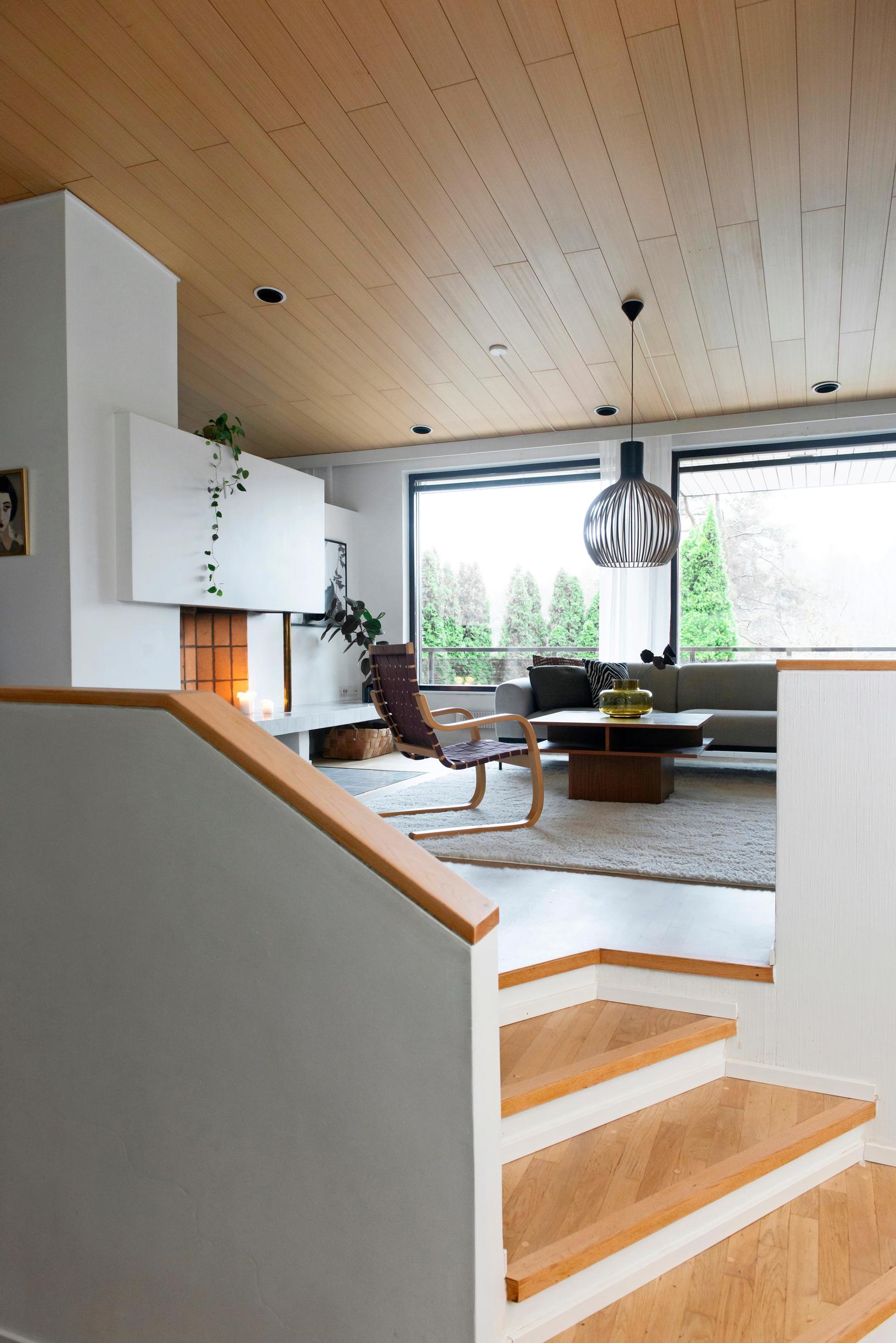 Image of a multi-level living room in a 1980s house, featuring an open fireplace and design furniture.