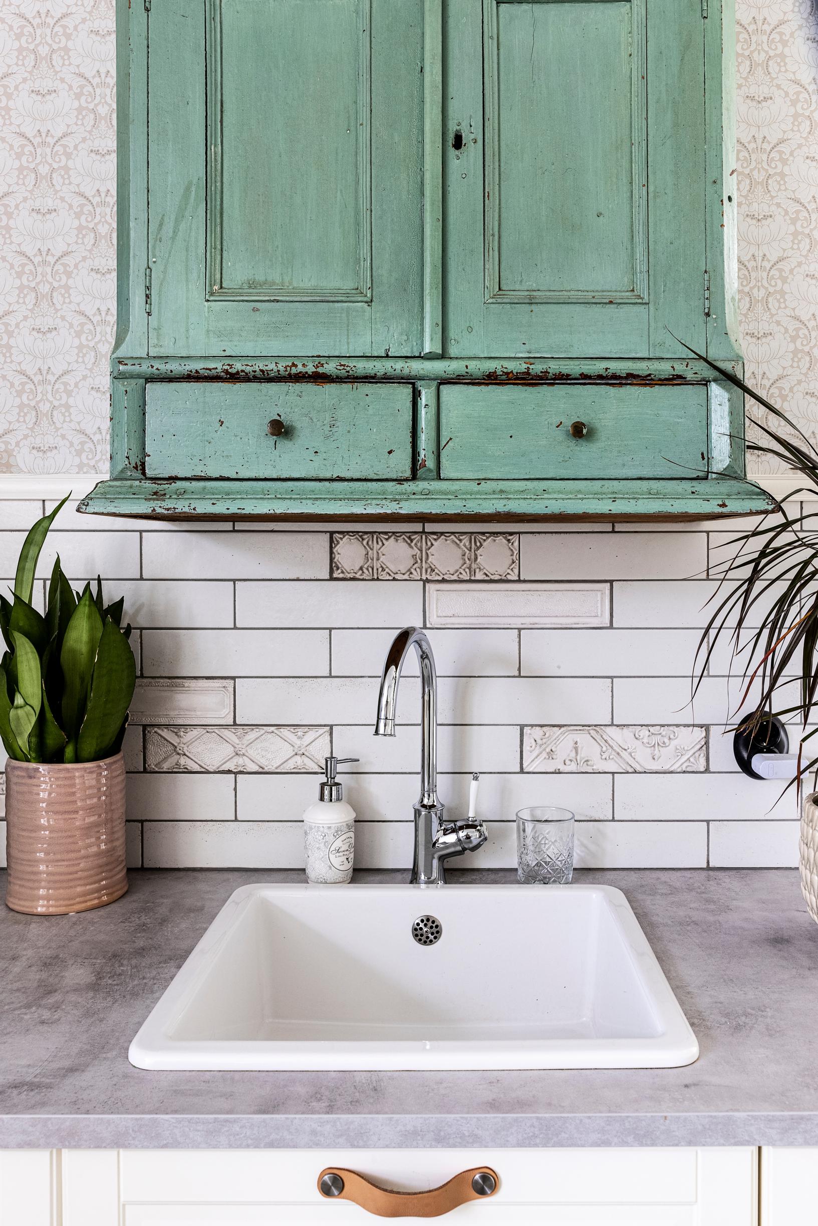 A green vintage wall cabinet above the sink