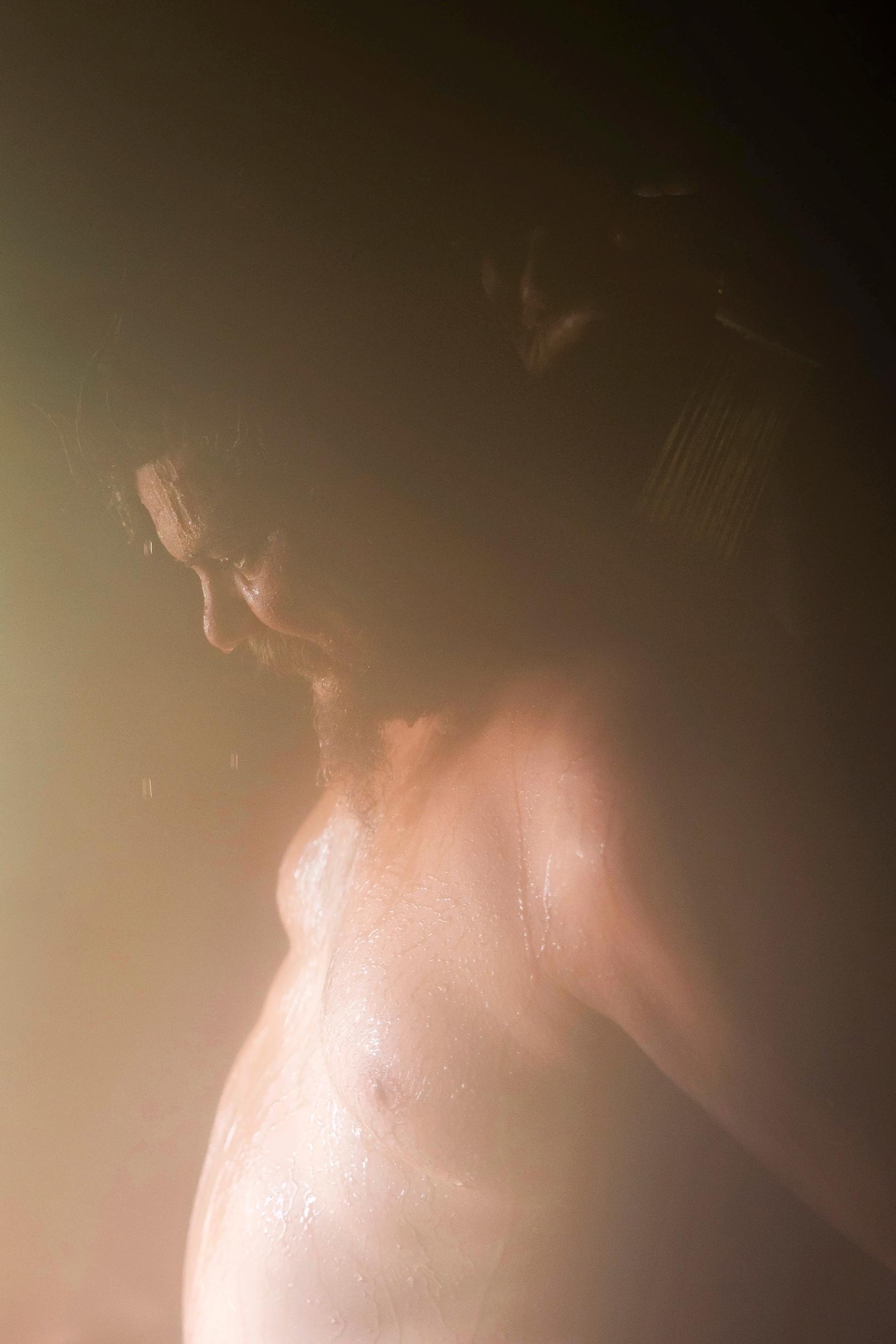 In the dimly lit sauna, a man looks downward.