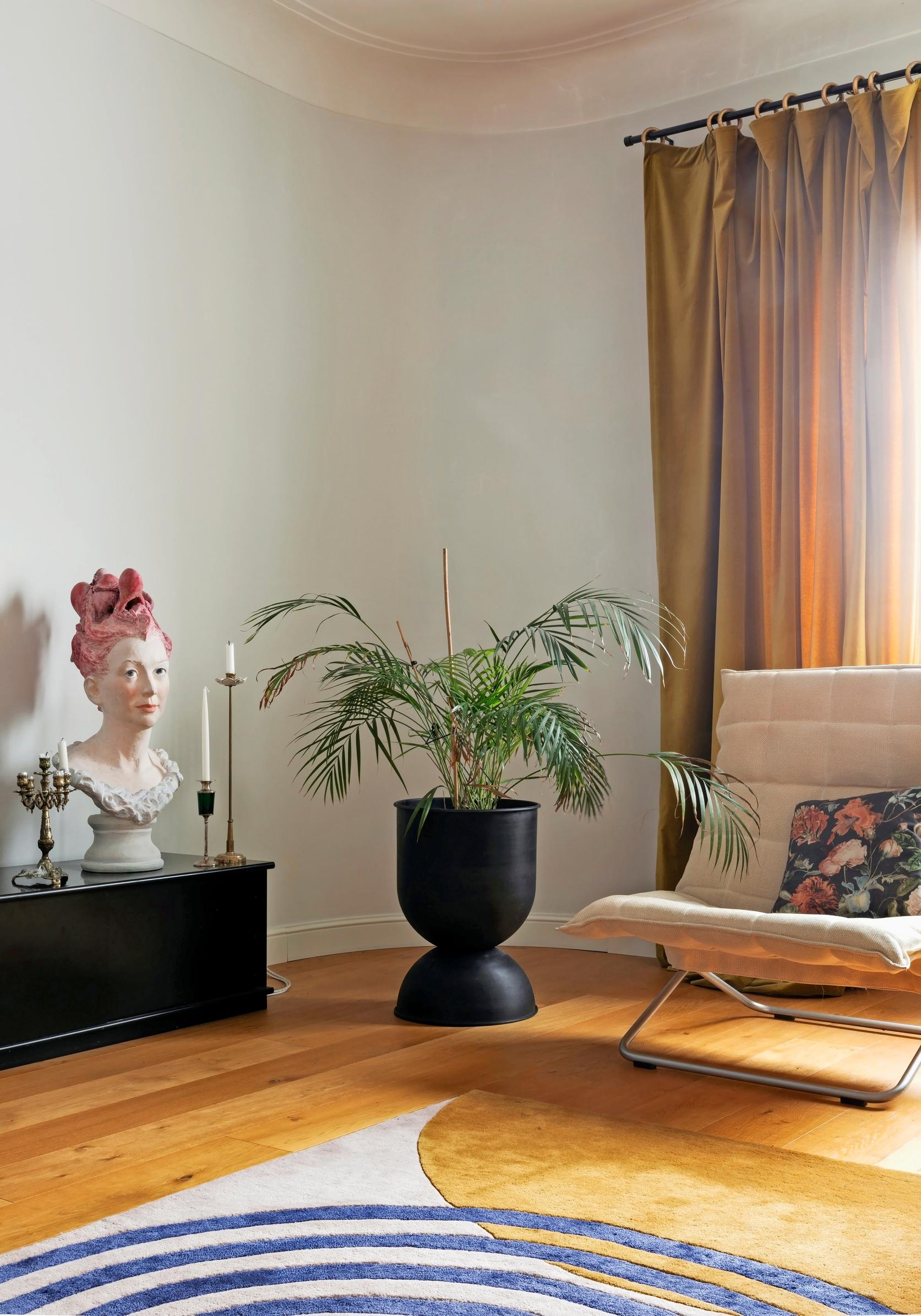 Living room with a rug, lounge chair, potted houseplant, and a low console.