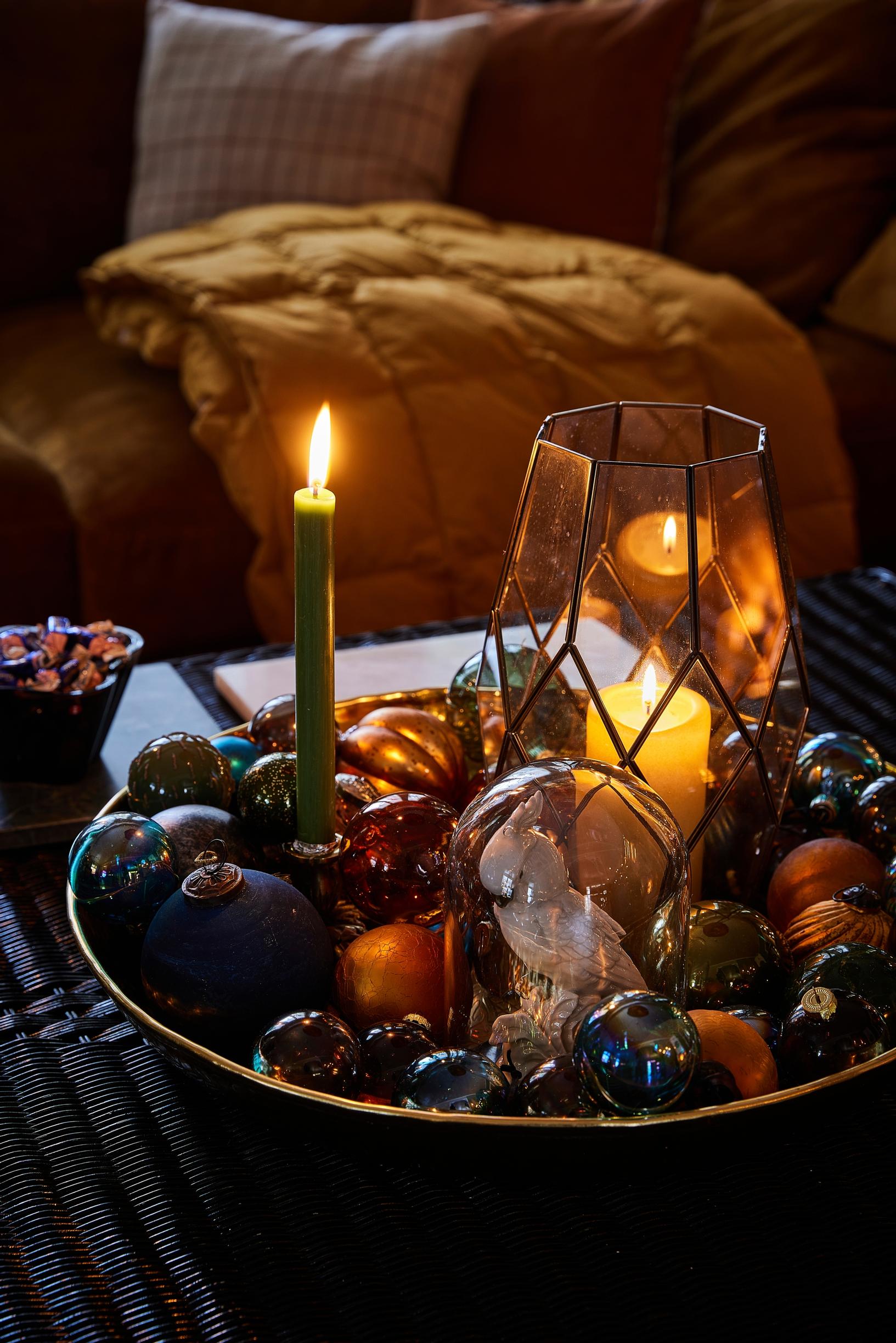 An arrangement of candles and Christmas ornaments on a platter.