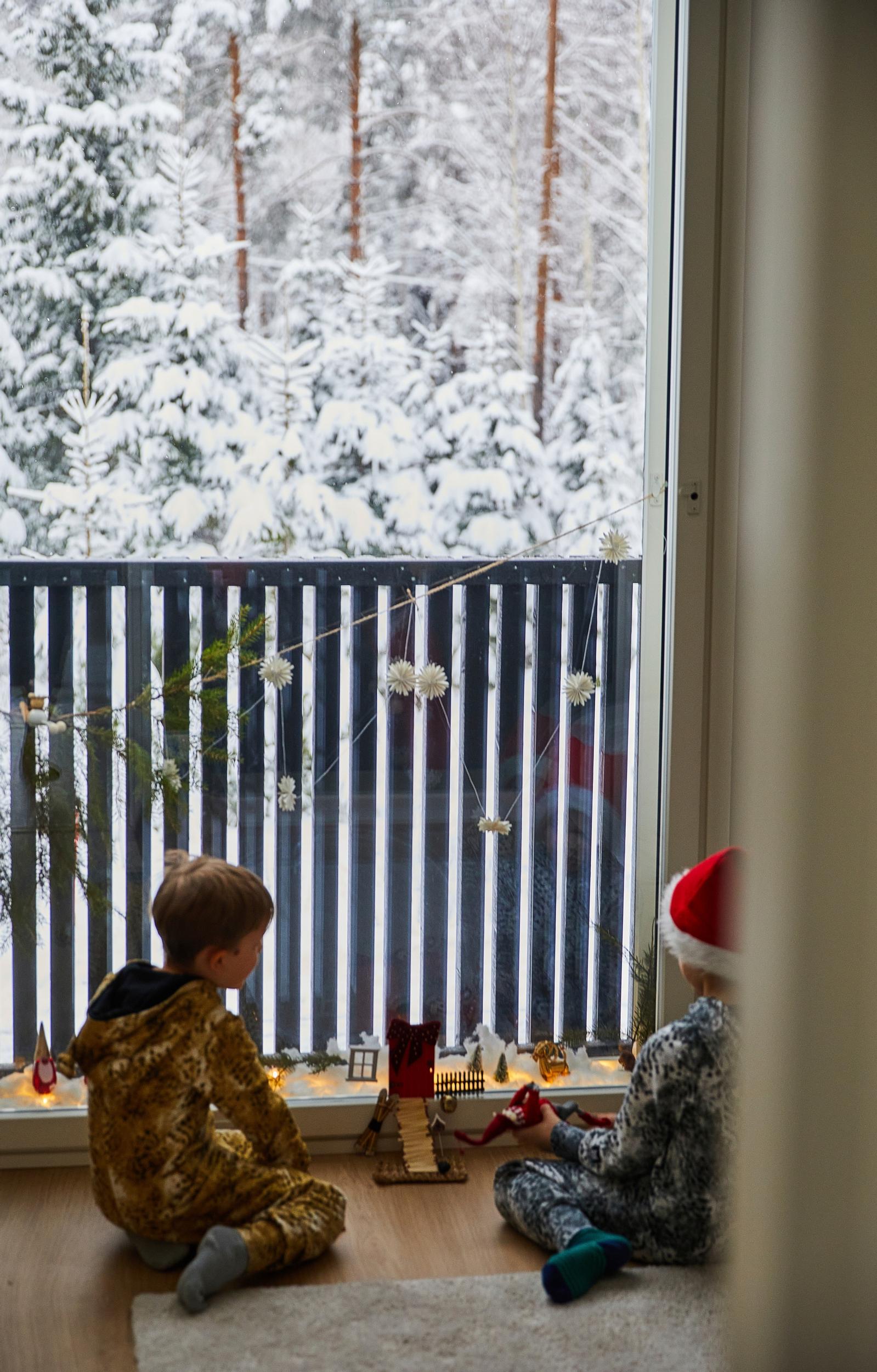little boys playing on the floor in front of the balcony, snowy forest in the background