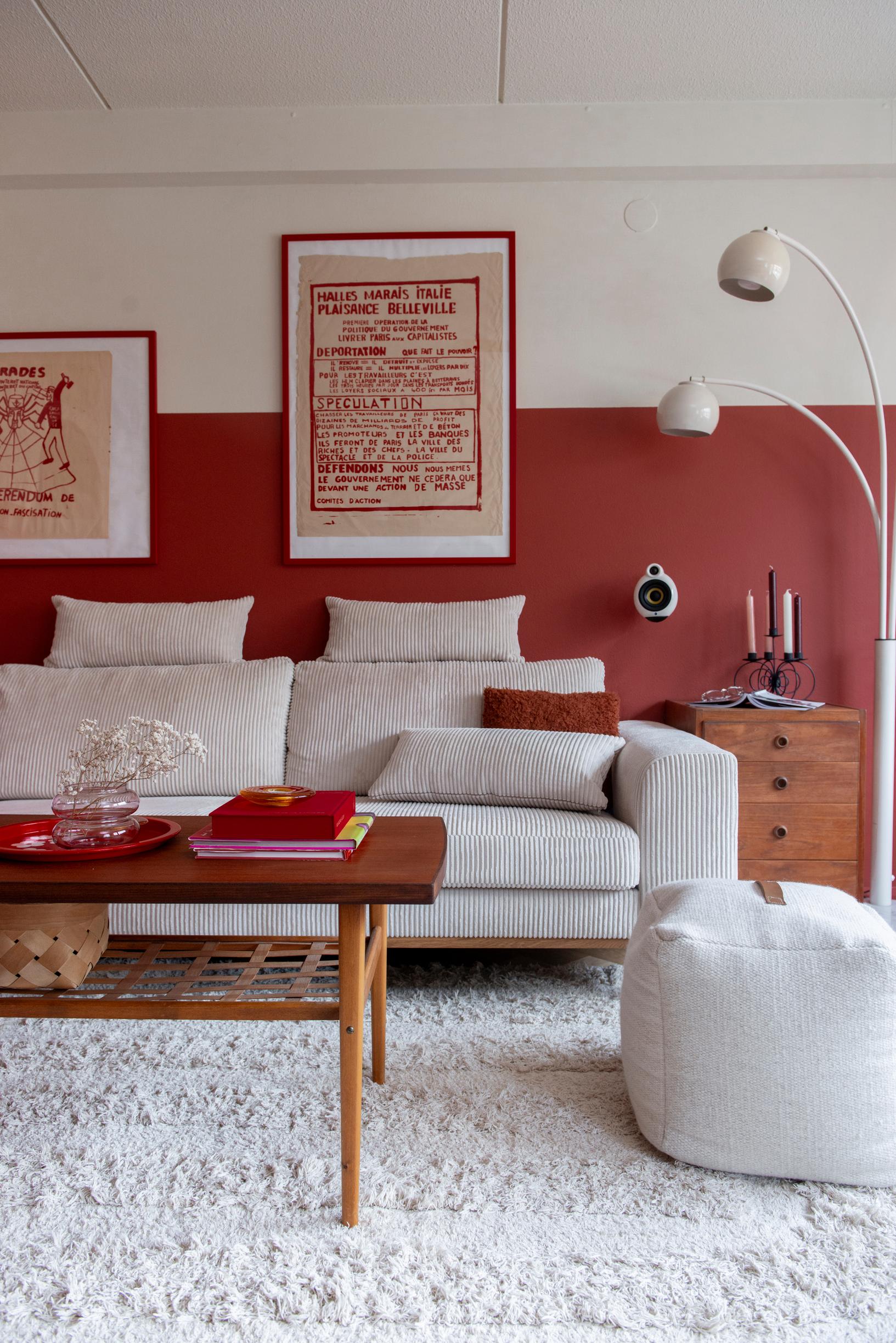 The lower part of the living room wall is painted red, with a white sofa placed against it.