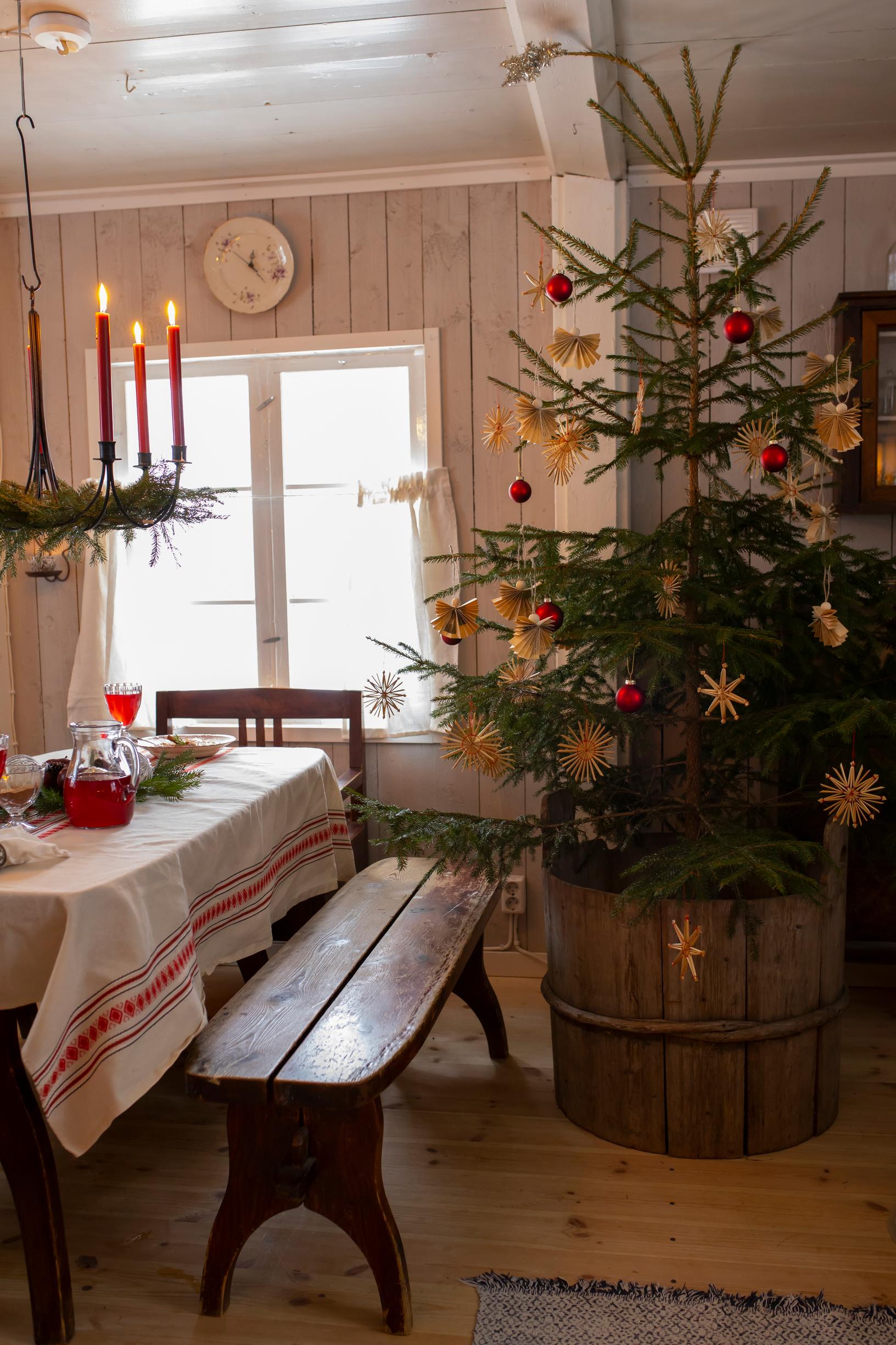 A Christmas tree in a large barrel and a dining set.
