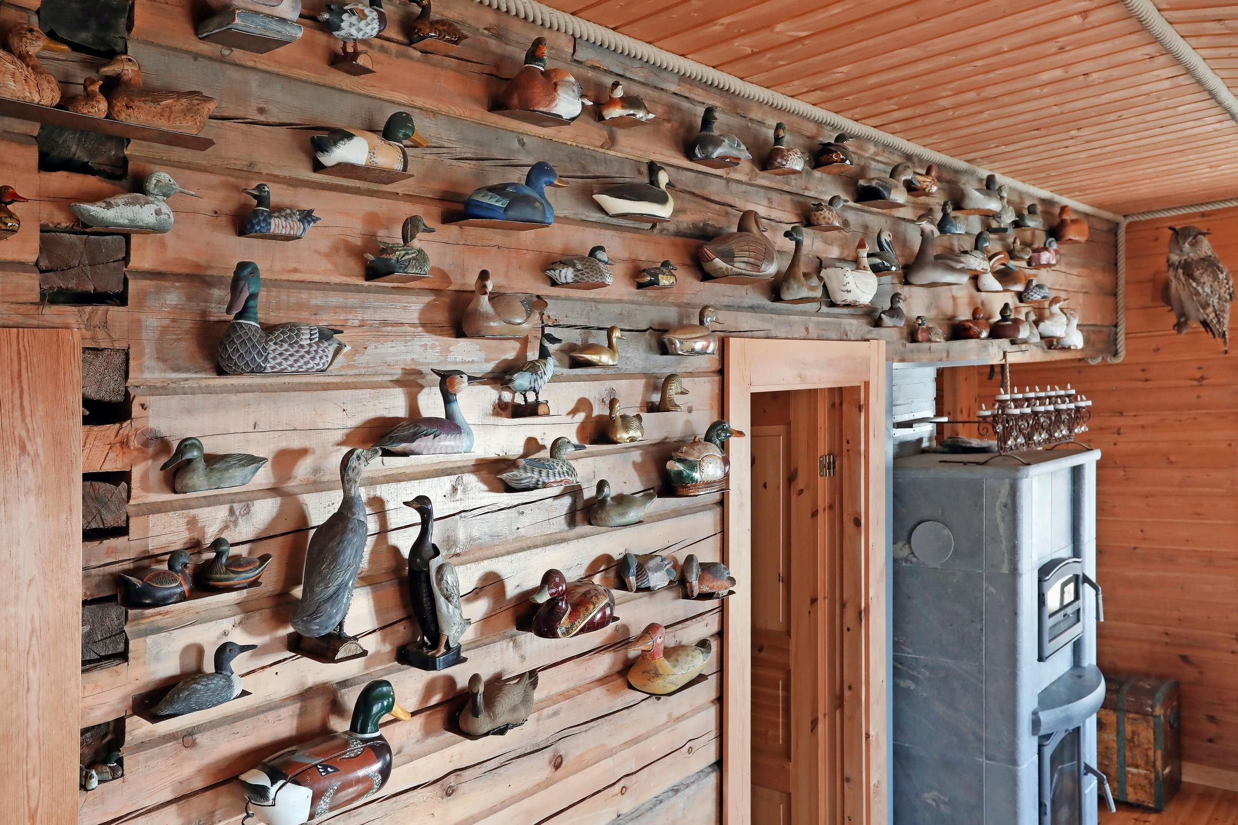 Decorative birds on a shelf against a log wall and a soapstone fireplace.