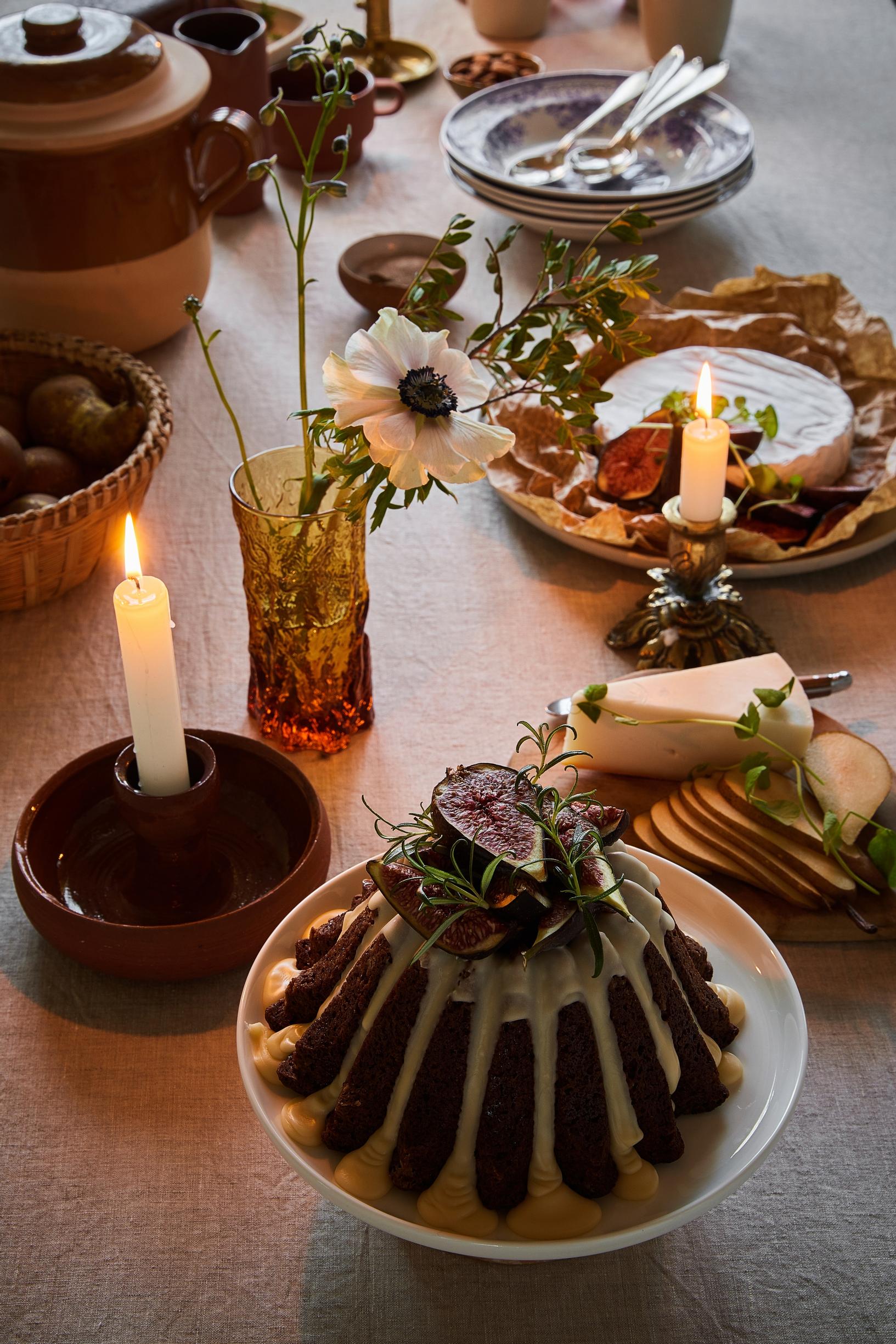 A Christmas cake, other holiday treats, candles, and flowers in a vase