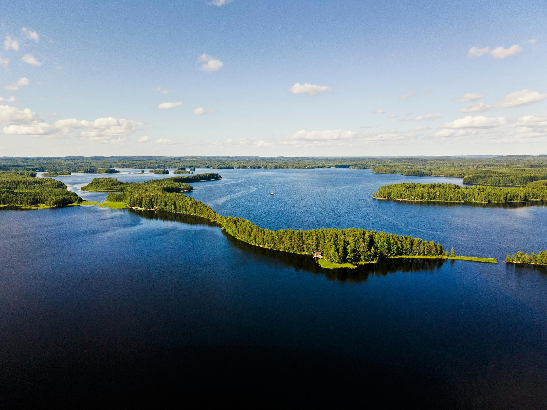 Aerial view of Lake Saimaa, lakes, islands, and forest with white clouds in the sky