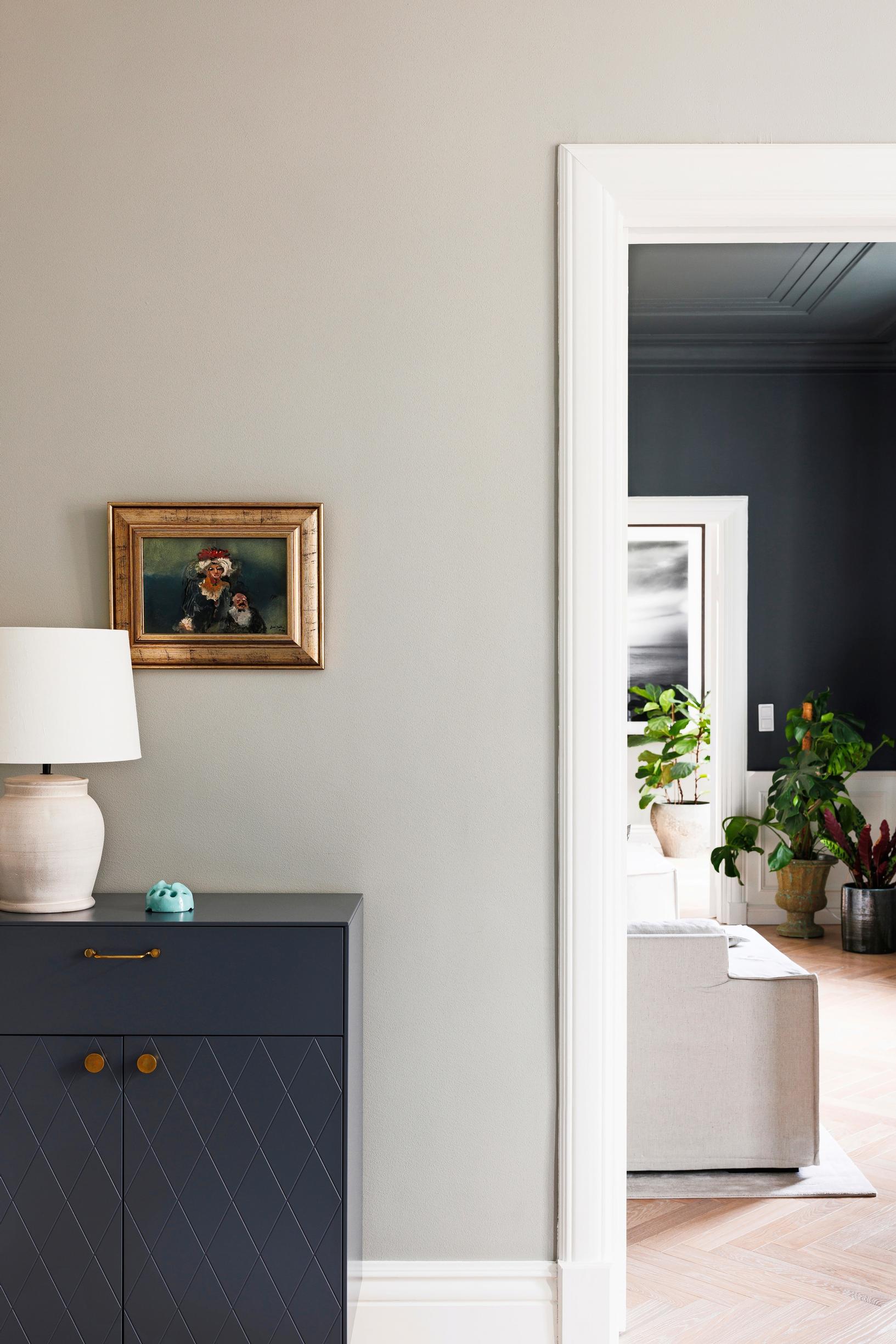 A dark blue dresser in the bedroom with a painting on top.